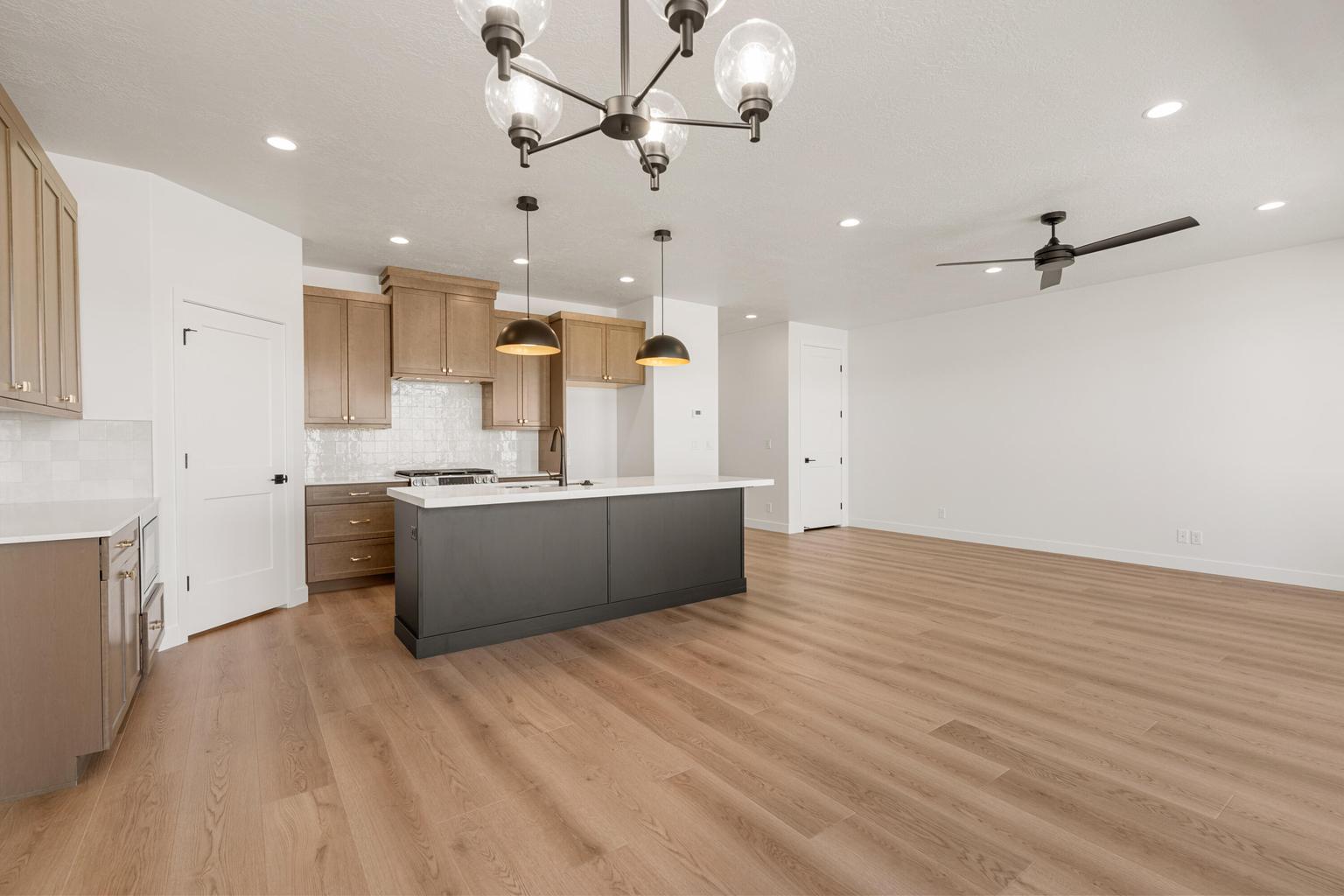 Open-concept kitchen and living area featuring wood-finish flooring, recessed lighting, and a contemporary chandelier