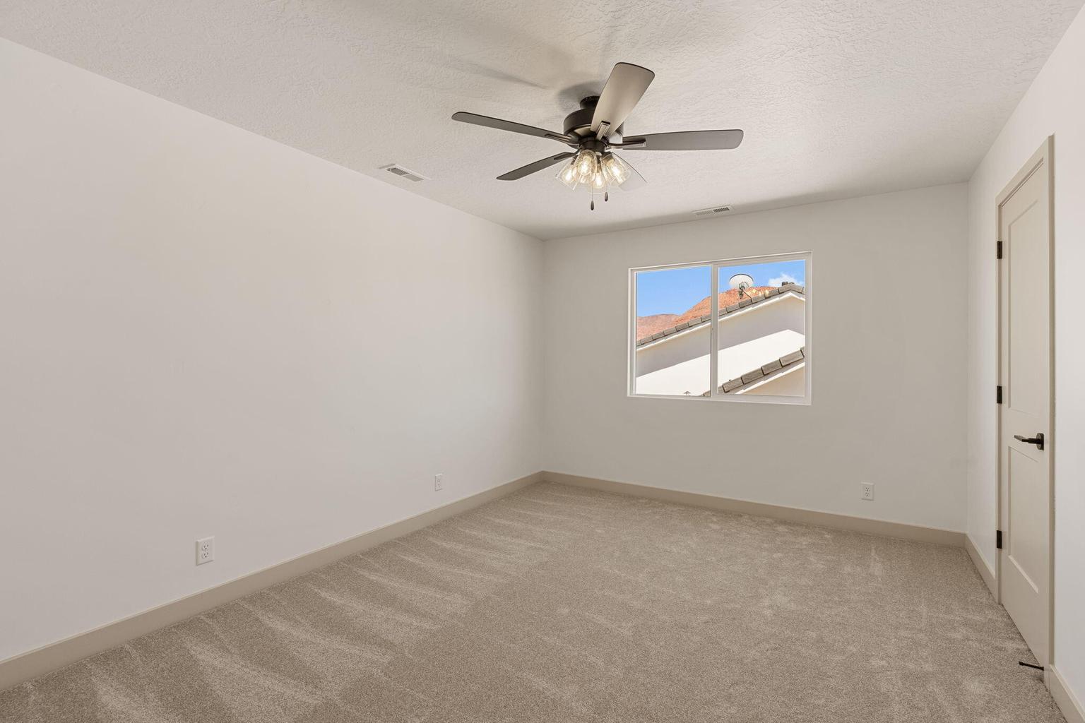 Spacious room featuring neutral carpeting, light-toned walls, and a ceiling fan with integrated lighting