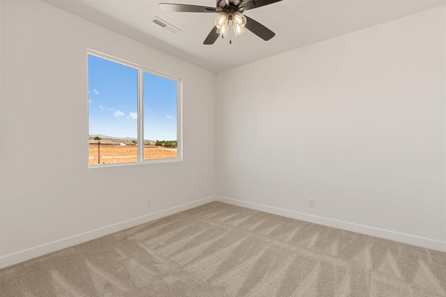 Bright room featuring a large window, neutral carpeting, white walls, and a ceiling fan with integrated lighting