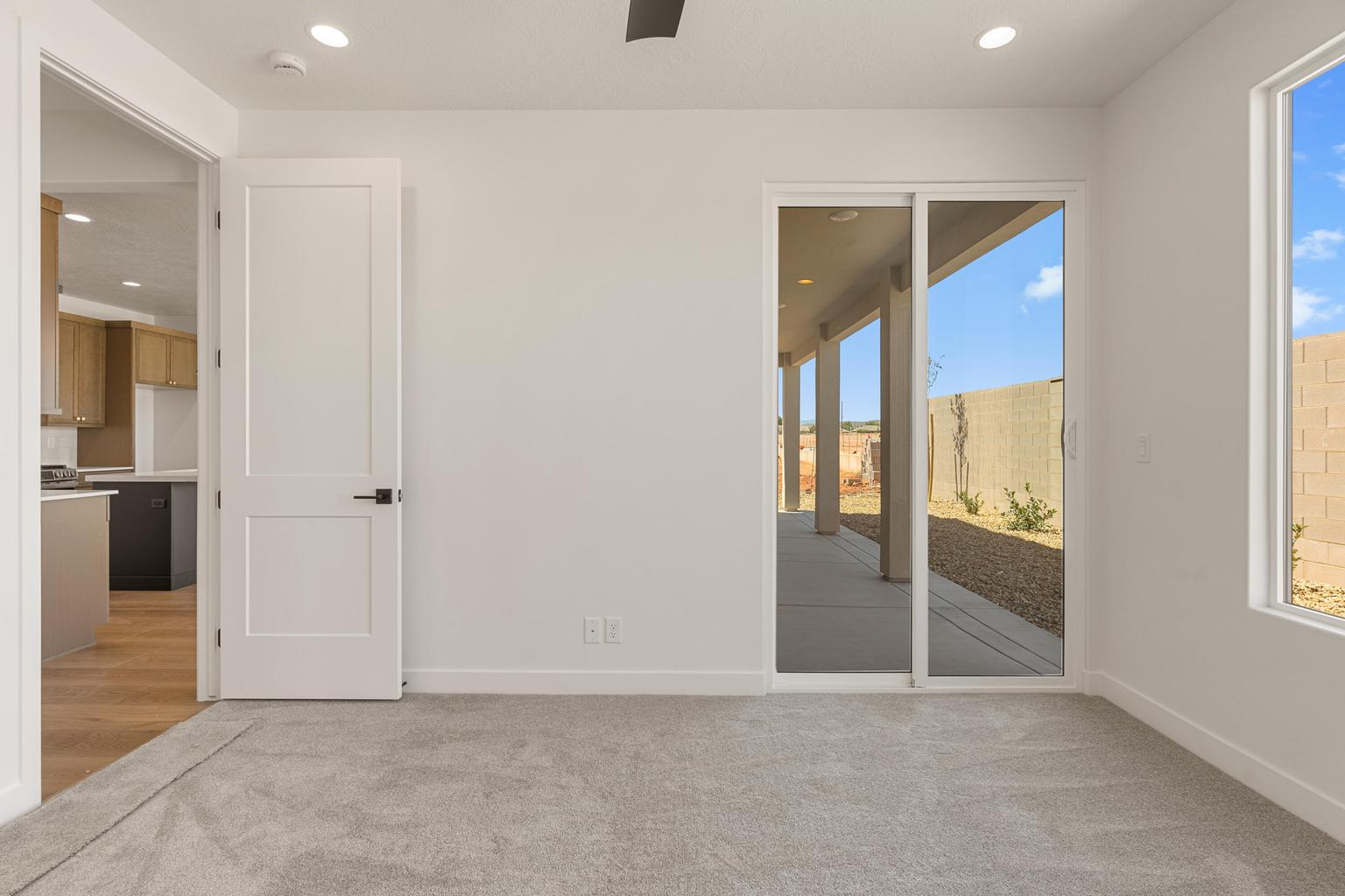 Indoor-outdoor living space featuring sliding glass door access to a covered patio, a recessed lighting package, light gray carpeting, and a flat-panel interior door with dark hardware