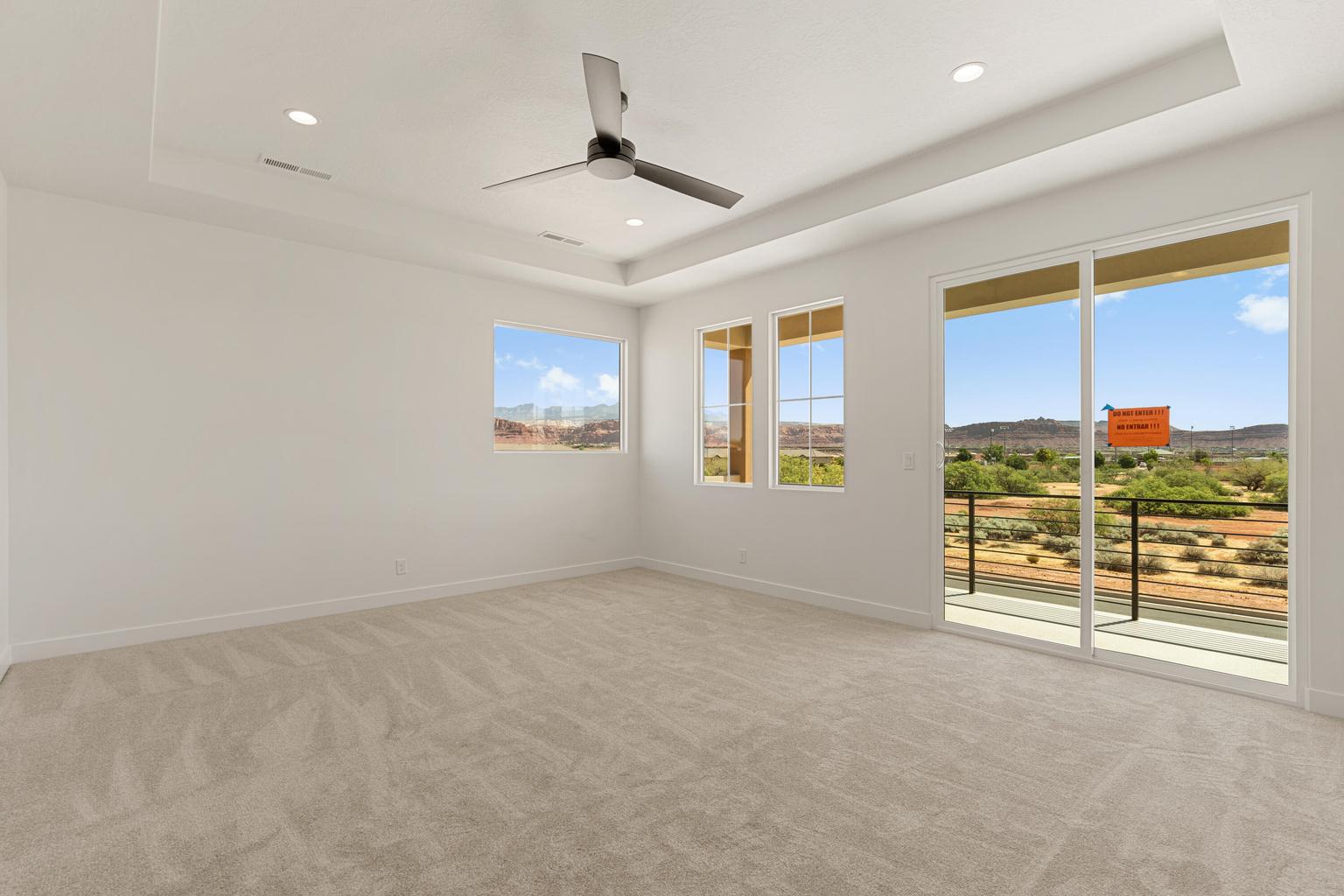 Bright room featuring a tray ceiling with recessed lighting and a ceiling fan