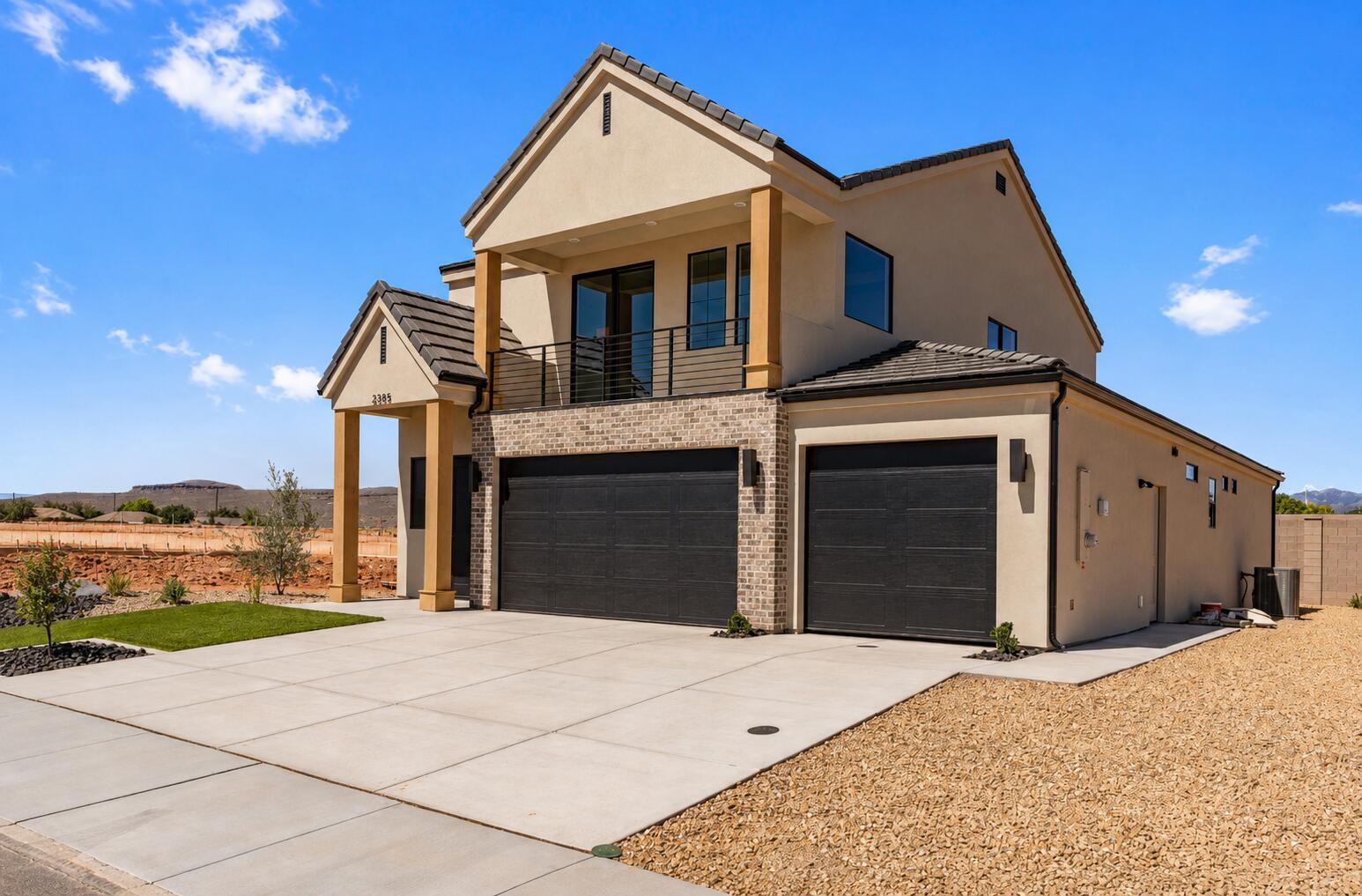 Contemporary stucco exterior with brick accents and a prominent second-story balcony