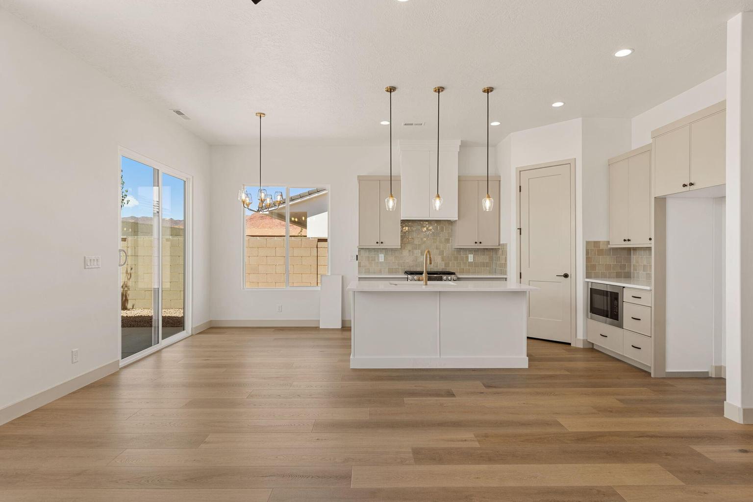 Open-concept kitchen and living area featuring wood-finish flooring, a kitchen island with pendant lighting, light-toned cabinetry, a tiled backsplash, and recessed lighting