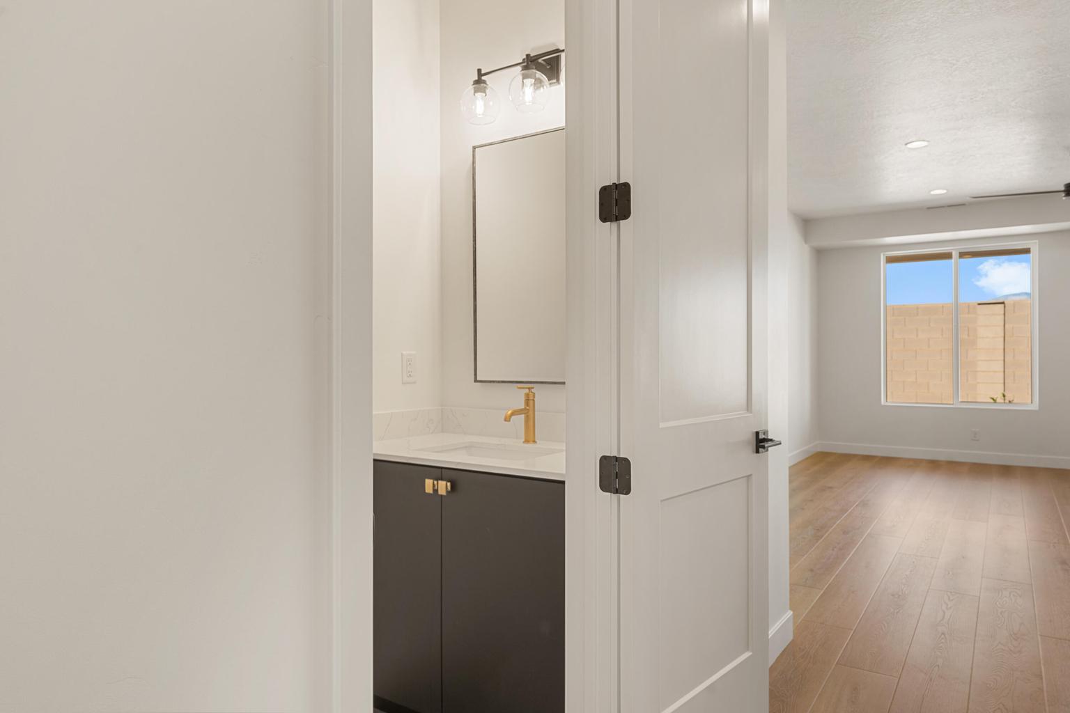 Bathroom vanity featuring a dark gray cabinet with gold-toned hardware, white countertop, and gold-toned faucet