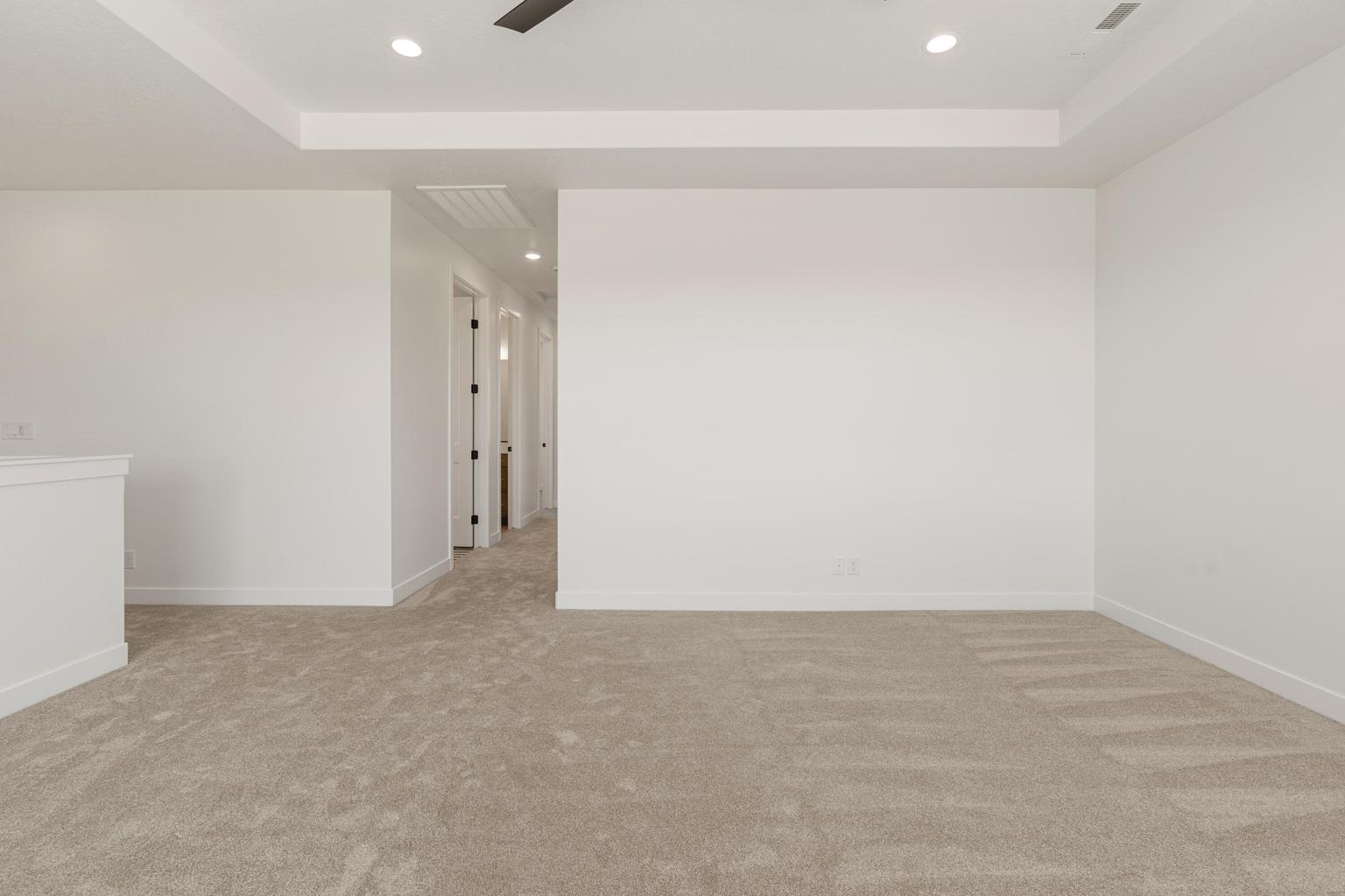 Carpeted room featuring a tray ceiling with recessed lighting and a ceiling fan