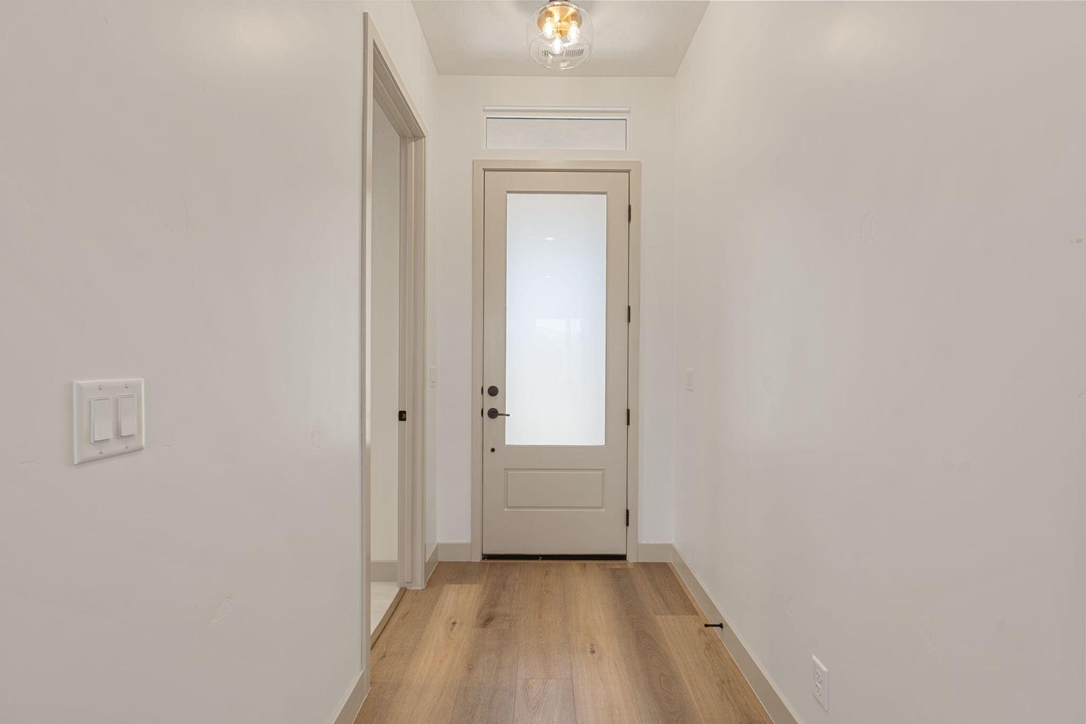 Entryway featuring a contemporary front door with frosted glass, wood-finish flooring, a modern flush-mount light fixture, and neutral wall tones