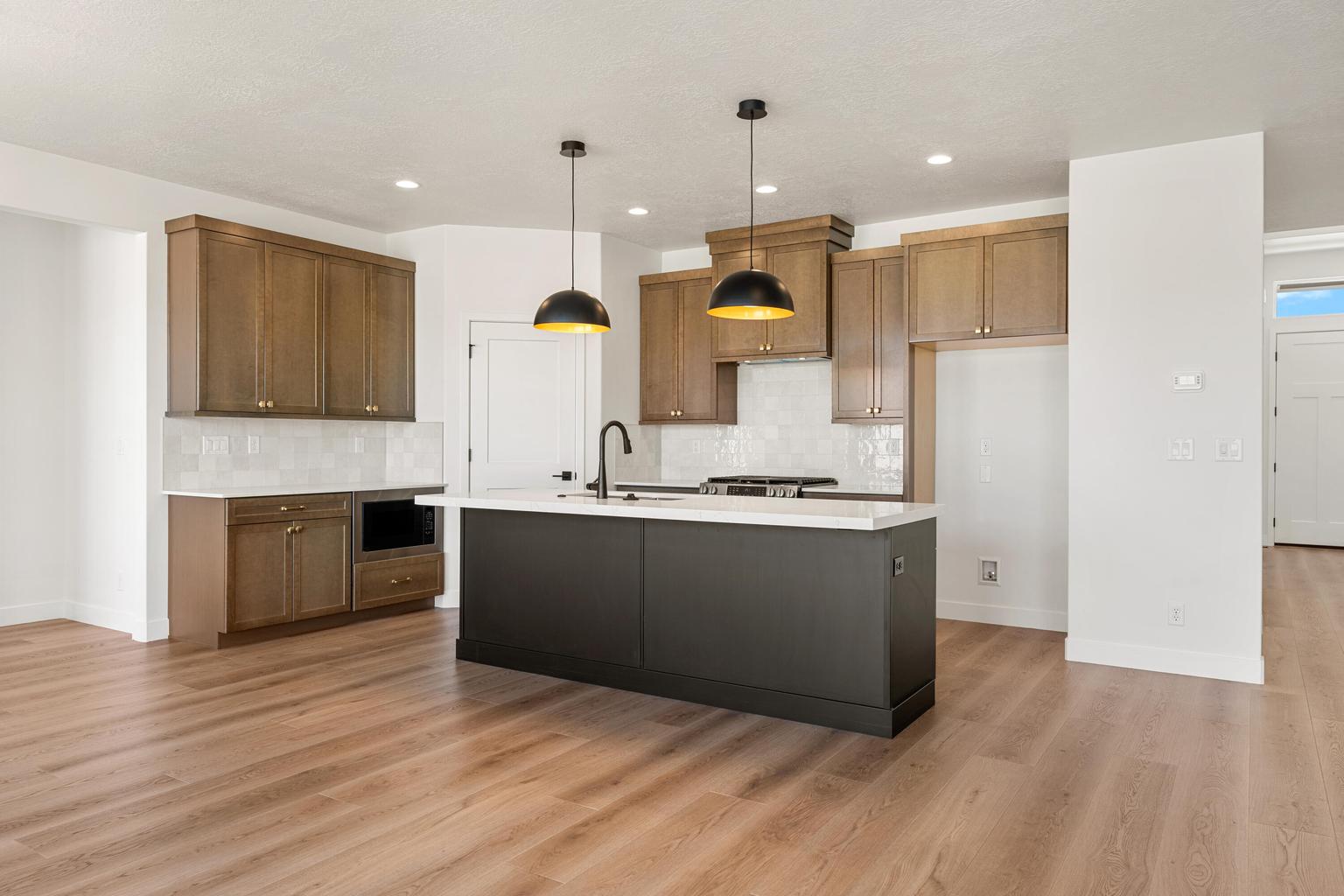 Contemporary kitchen featuring a dark island with a light-toned countertop, wood-finish flooring, and recessed lighting