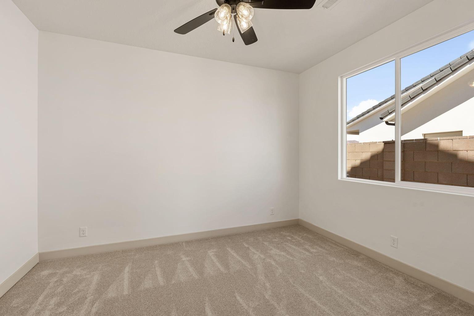 Carpeted room featuring a ceiling fan with integrated lighting, a large window, white walls, and light-colored baseboards