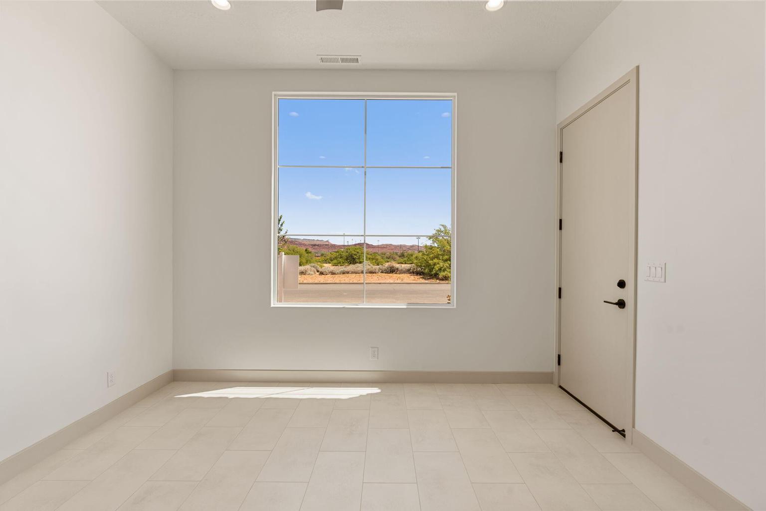 Bright interior space featuring a large transom window, light tile flooring, and a modern door with matte black hardware