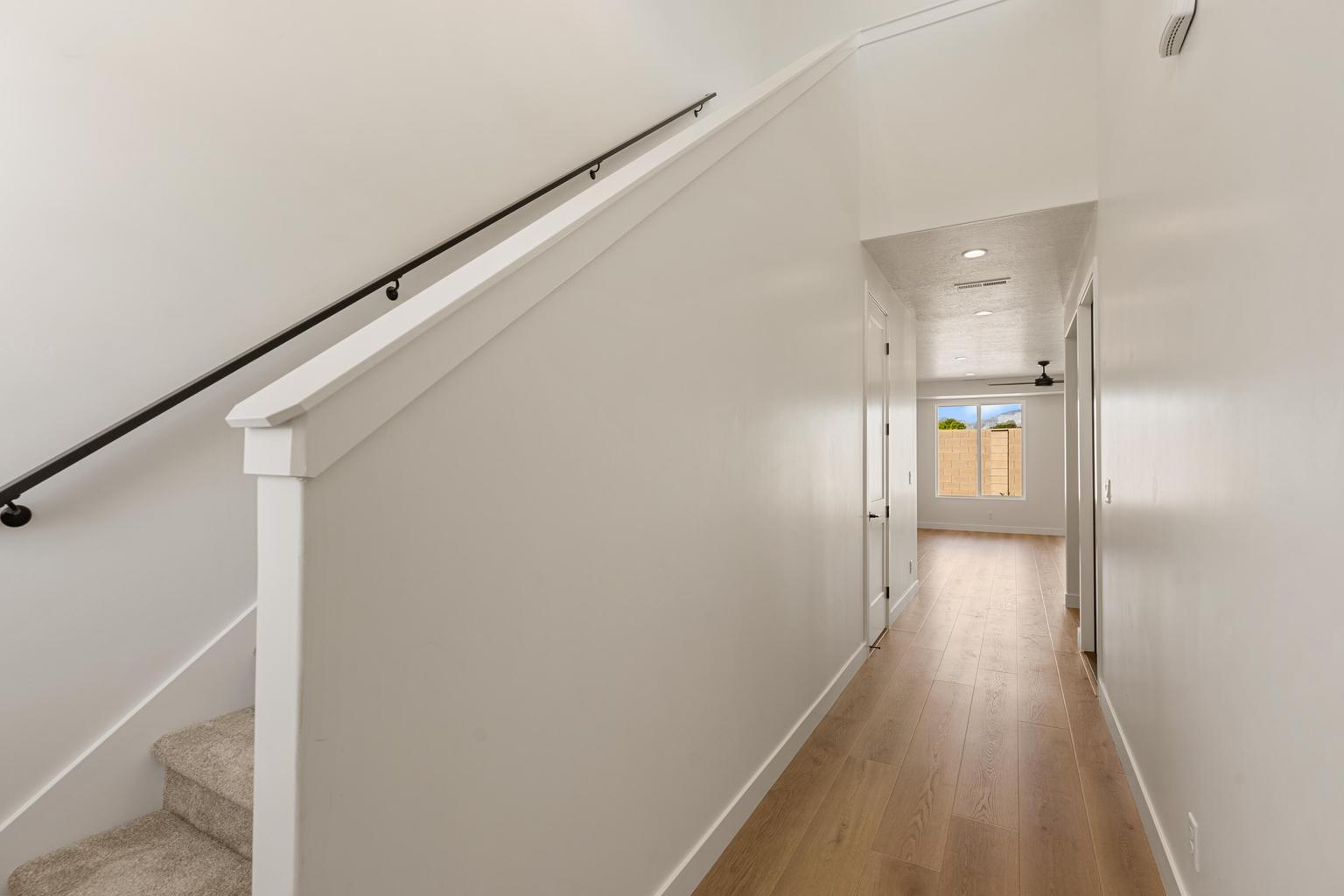 Contemporary hallway featuring light wood-finish flooring, recessed lighting, and a white trim package