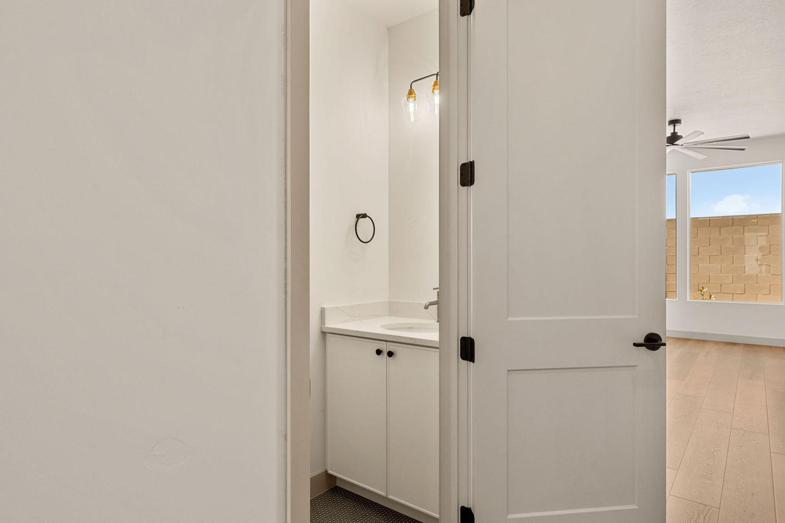 Powder room featuring a white vanity with a countertop, undermount sink, and wall-mounted light fixture