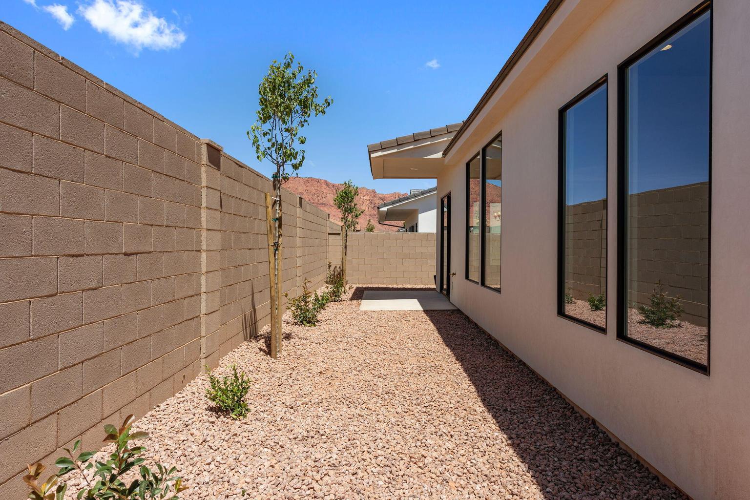 Private side yard with gravel landscaping, established plantings, and a block wall perimeter