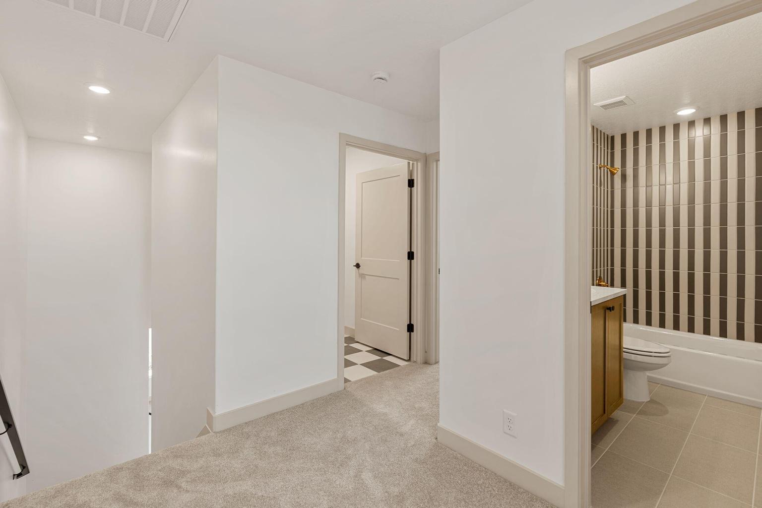 Hallway featuring recessed lighting, light-colored carpeting, and white walls