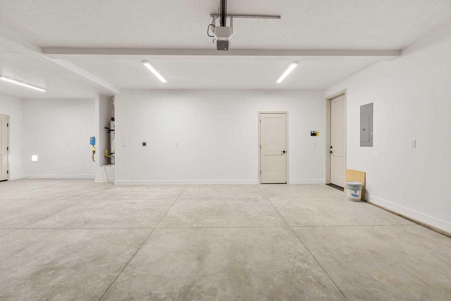 Spacious garage featuring a concrete floor, multiple doors, and overhead lighting