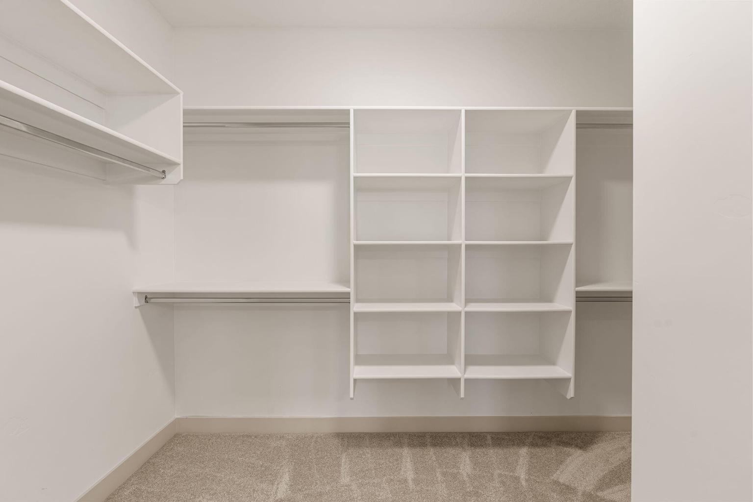 Custom closet system featuring multiple hanging rods and integrated shelving units, all in a crisp white finish