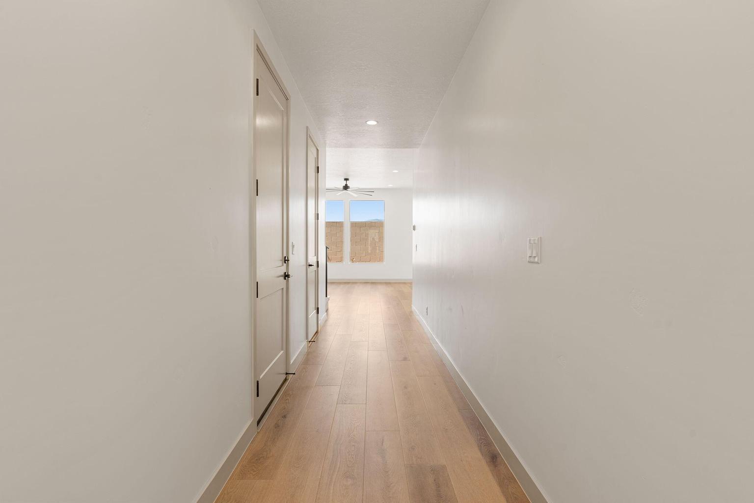 Hallway featuring light wood-finish flooring, white walls, and contemporary interior doors