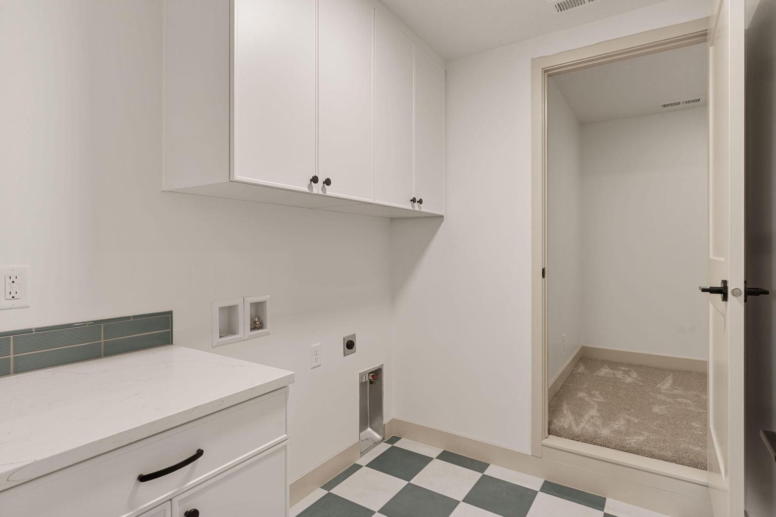 Laundry area featuring checkerboard flooring, white cabinetry, a countertop with a subway tile backsplash, and a separate utility closet with carpet