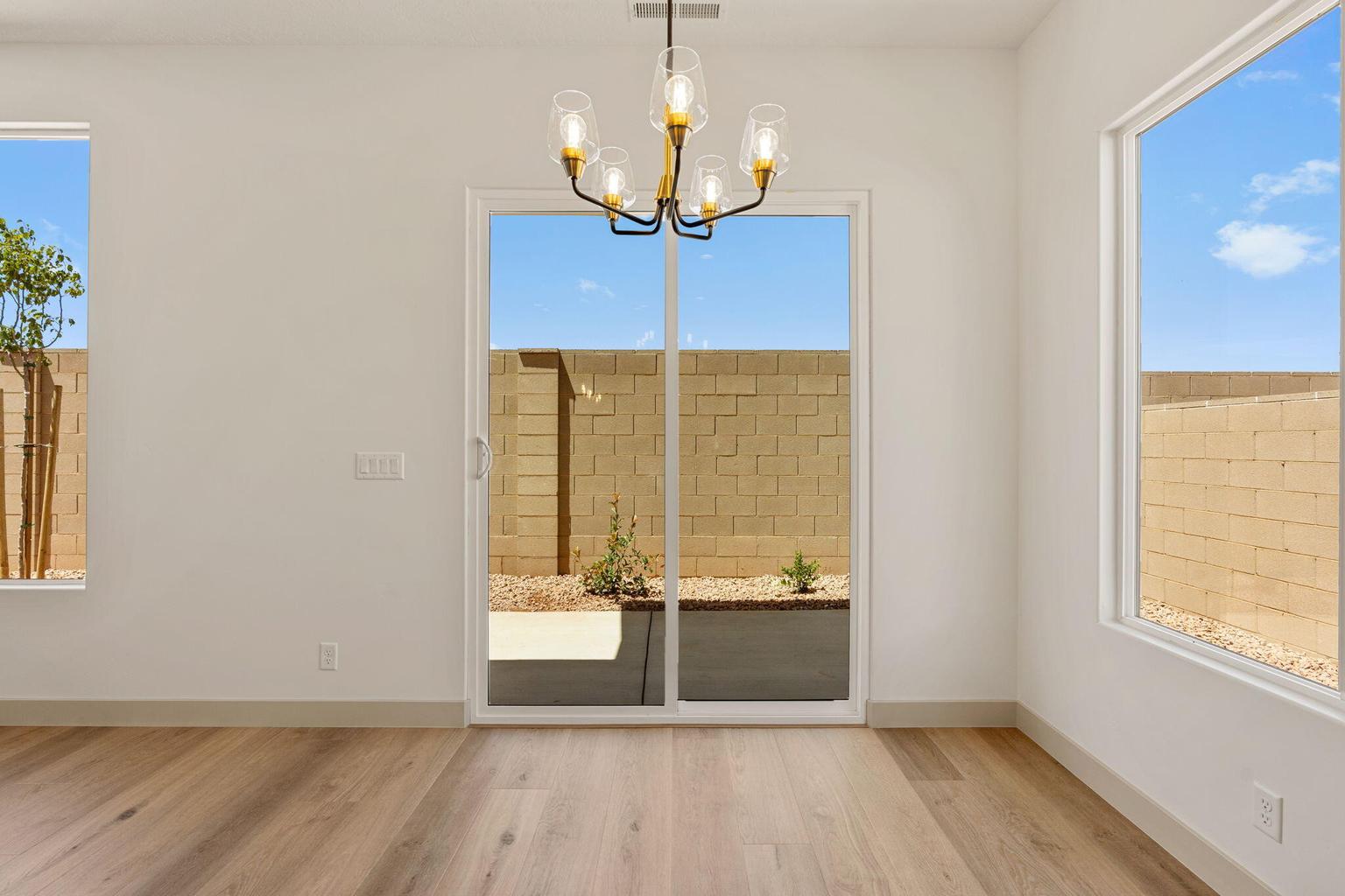 Spacious room with wood-finish flooring, a modern chandelier, and a sliding glass door providing access to the exterior