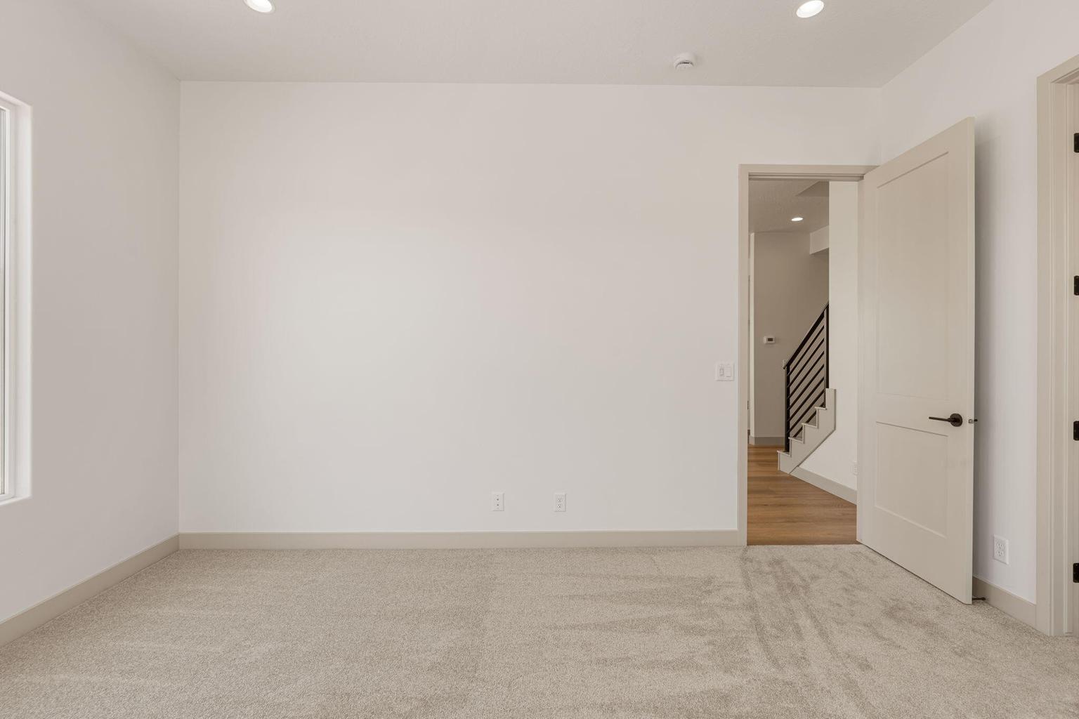 Spacious room featuring neutral carpeting, white walls, and recessed lighting