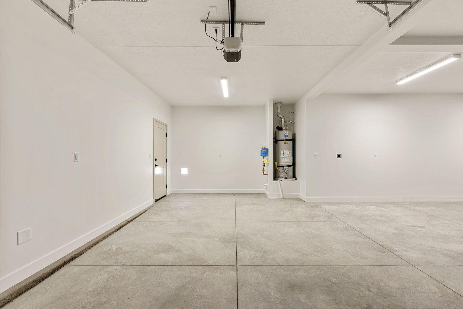 Spacious garage with concrete flooring, bright overhead lighting, and white painted walls