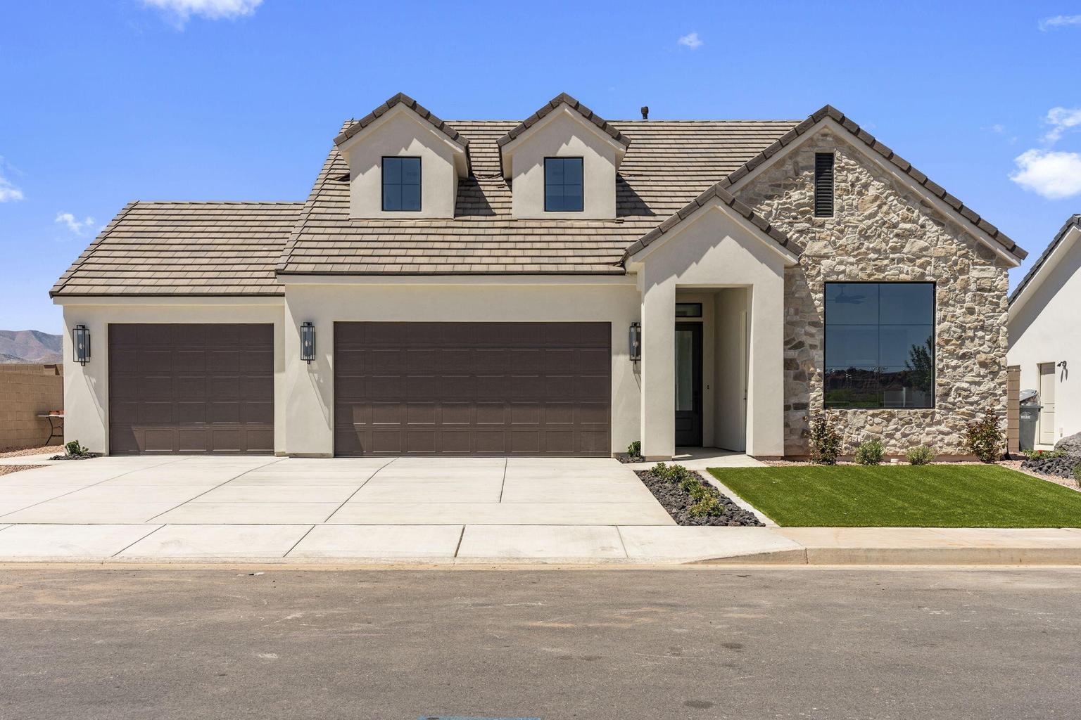 Stone and stucco facade with a two-car garage and dormer windows