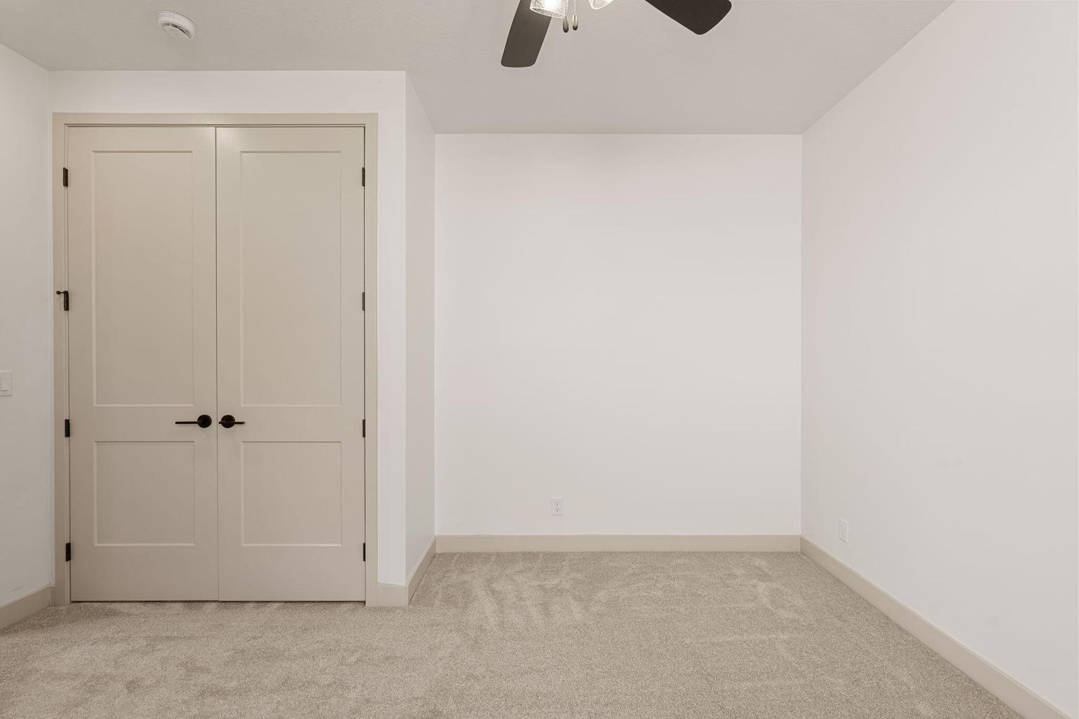 Double panel doors with black hardware, neutral carpet flooring, and white baseboards