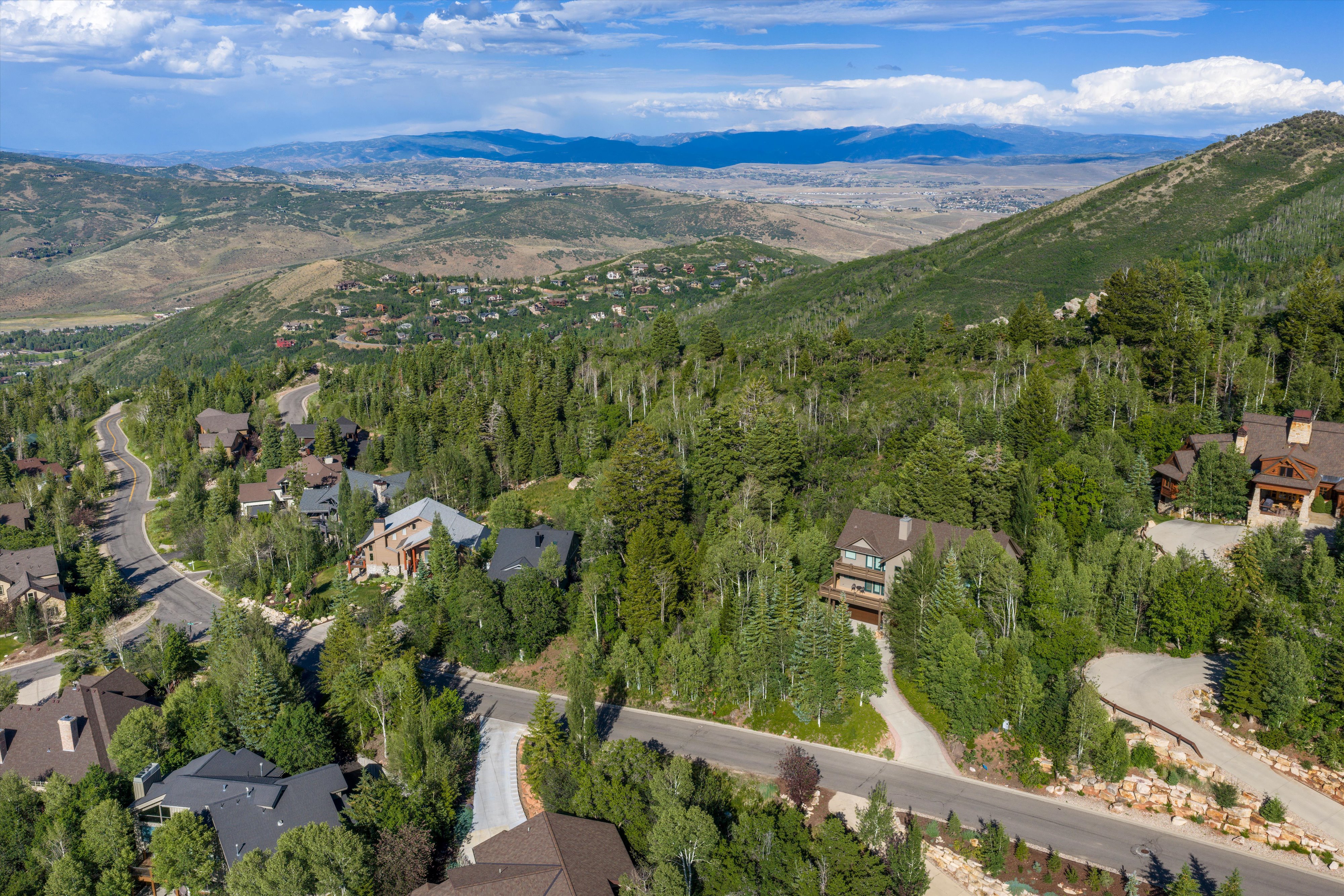 Mountainous terrain with scattered residential properties, winding roads, and extensive tree coverage