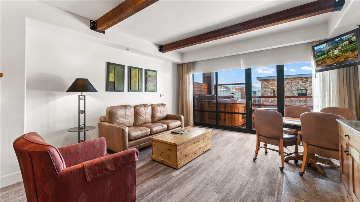 Open-concept living area featuring wood-finish flooring and exposed ceiling beams