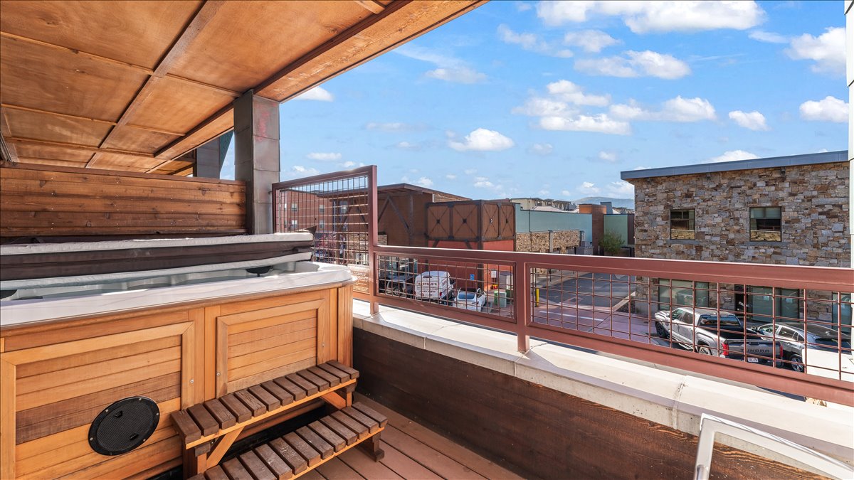 Outdoor spa with wood-finish siding, integrated steps, and a partially covered patio area