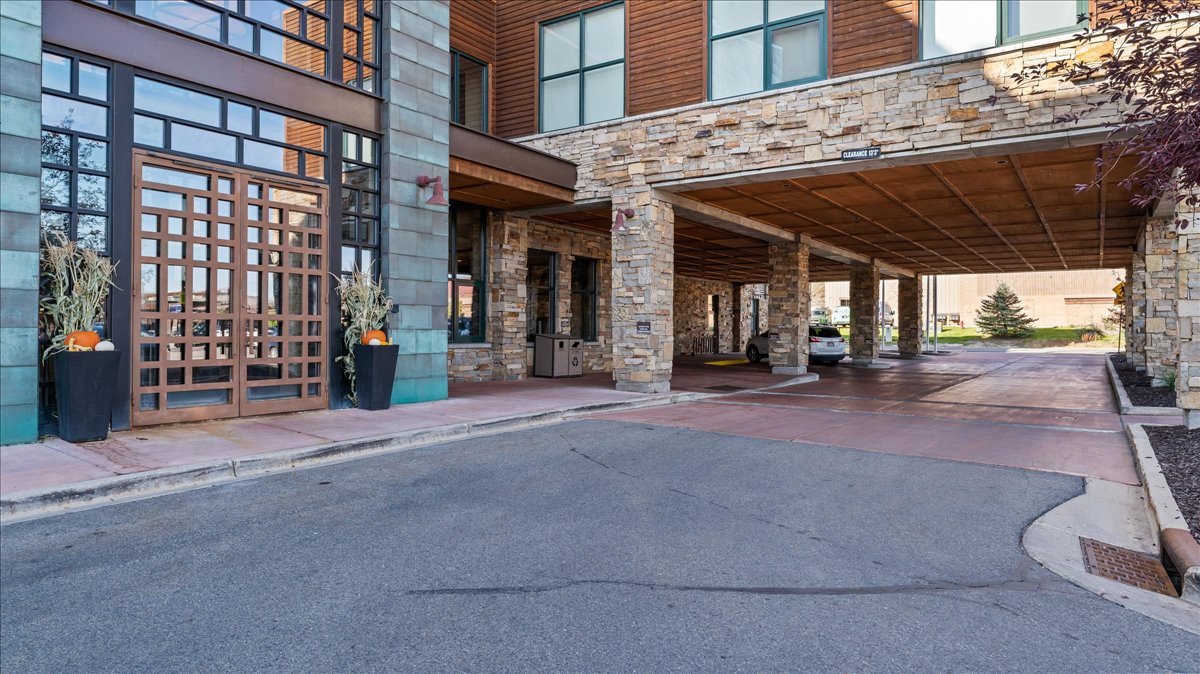 Exterior featuring a stone facade, a multi-pane glass entry, and a covered drive-through portico with stone columns