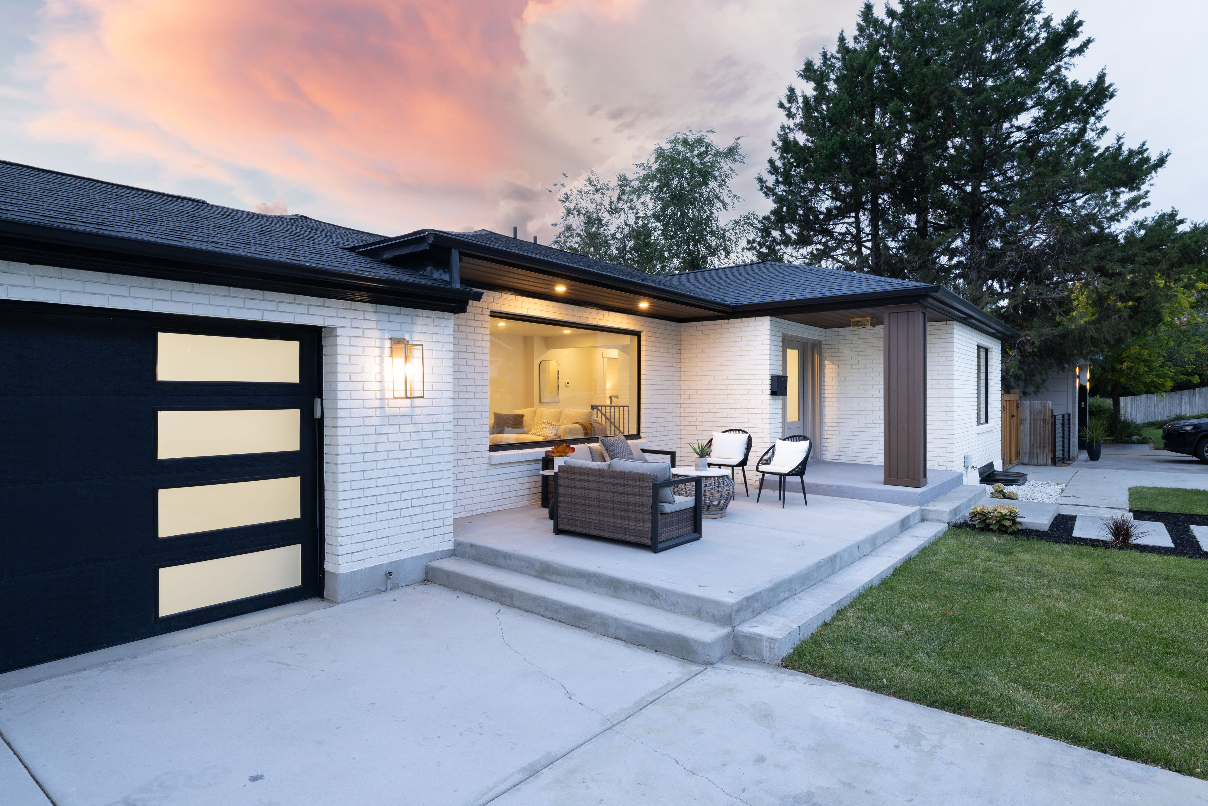 Modern exterior featuring white brick siding, a dark asphalt shingle roof, and a black garage door with horizontal frosted panels