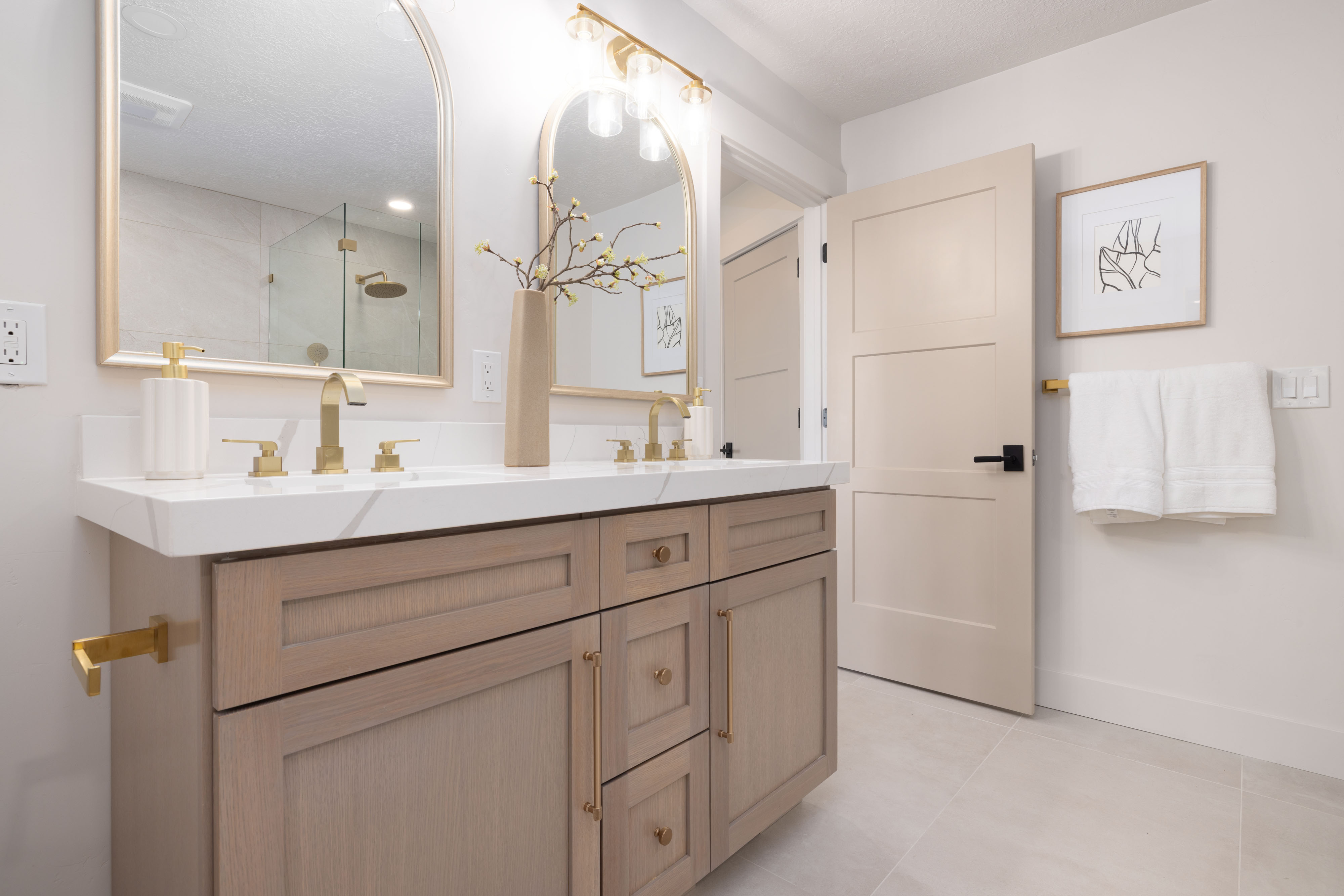 Double vanity featuring wood-finish cabinetry, white countertop, and gold-tone fixtures