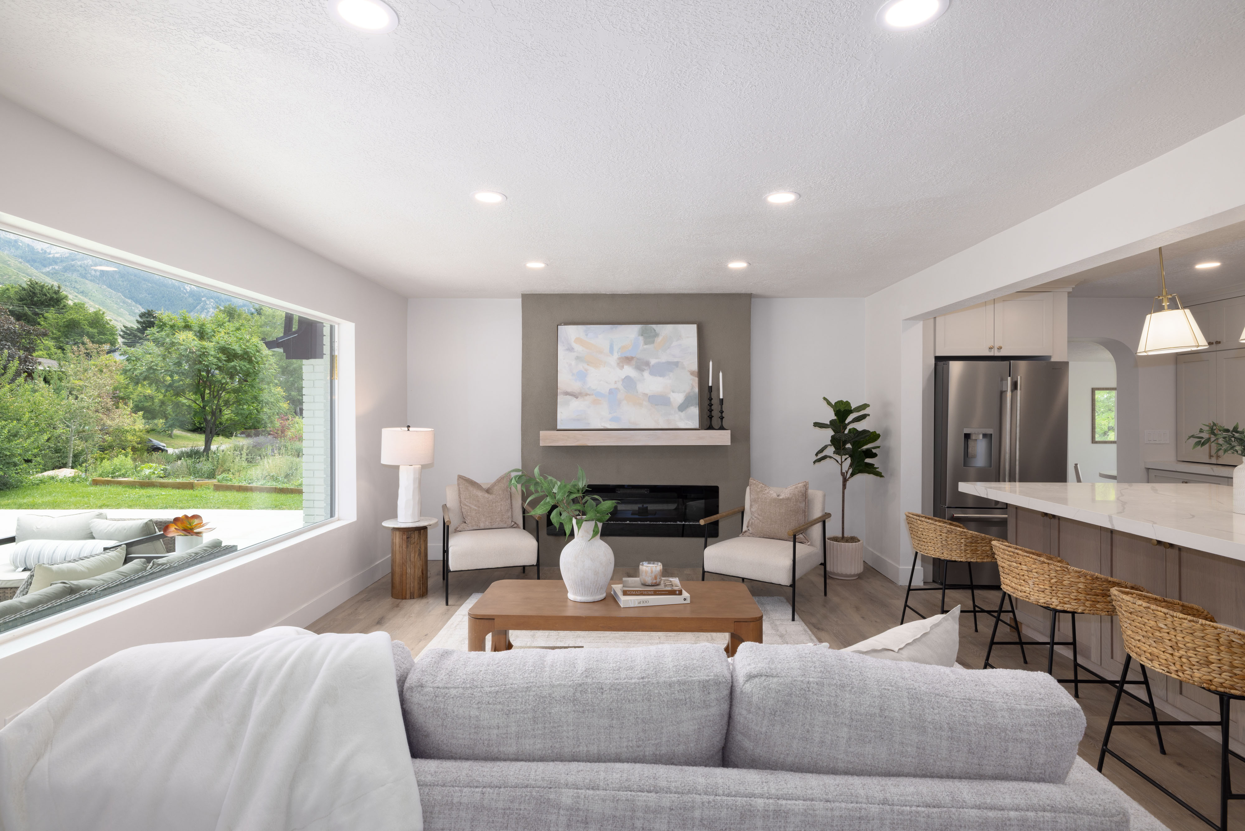 Living area featuring a floor-to-ceiling window, a contemporary fireplace with a stone-finish surround, a wood mantel, and recessed lighting