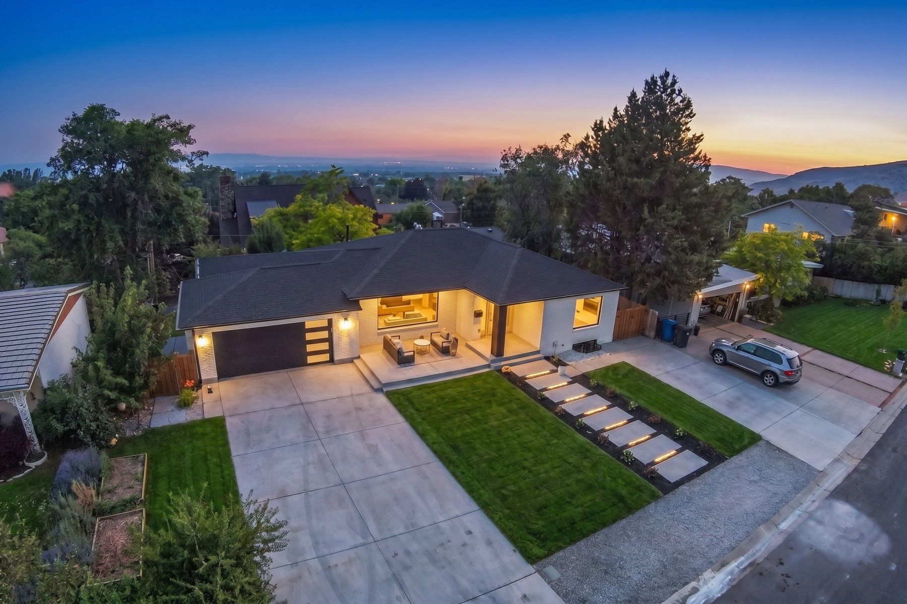 Modern single-story residence with a dark shingle roof, light-toned exterior, and an attached two-car garage