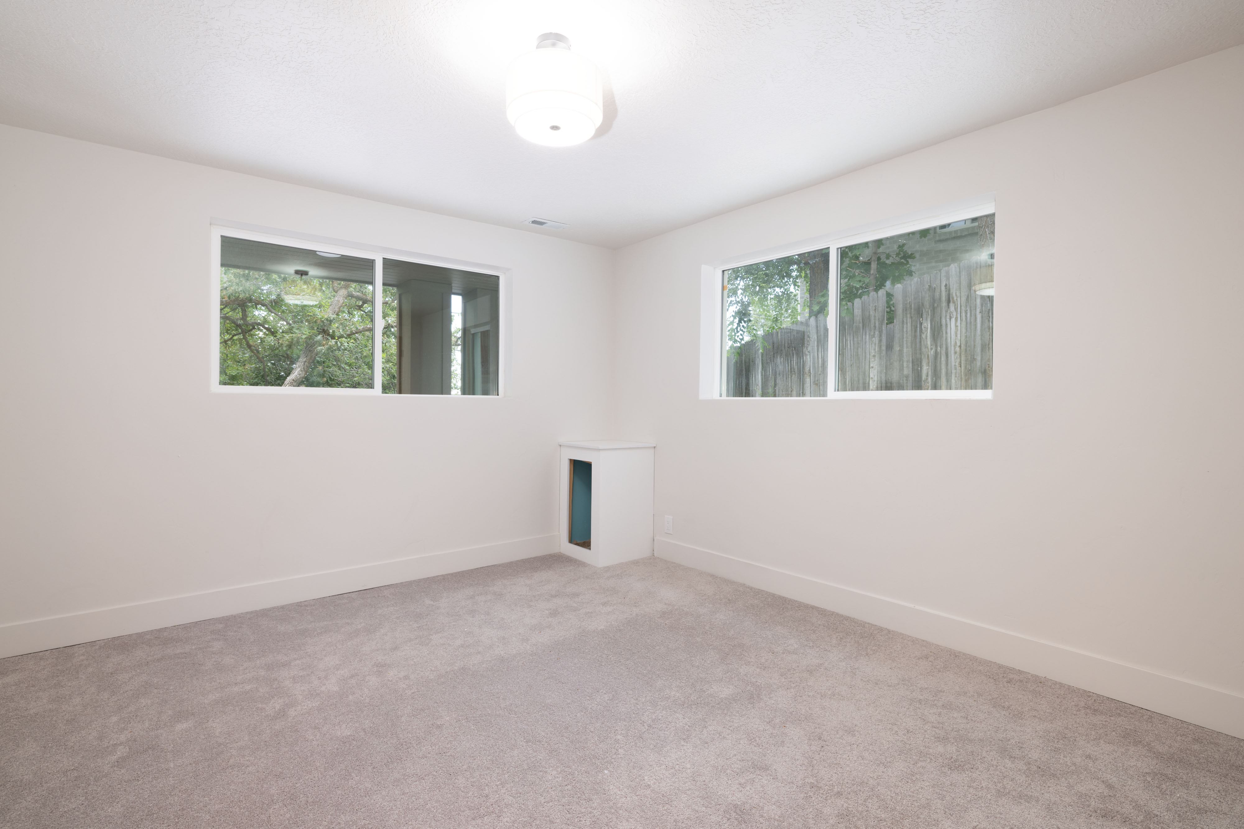 Neutral tone wall paint with a textured ceiling finish, two windows, wall-to-wall carpeting, and a built-in wall niche