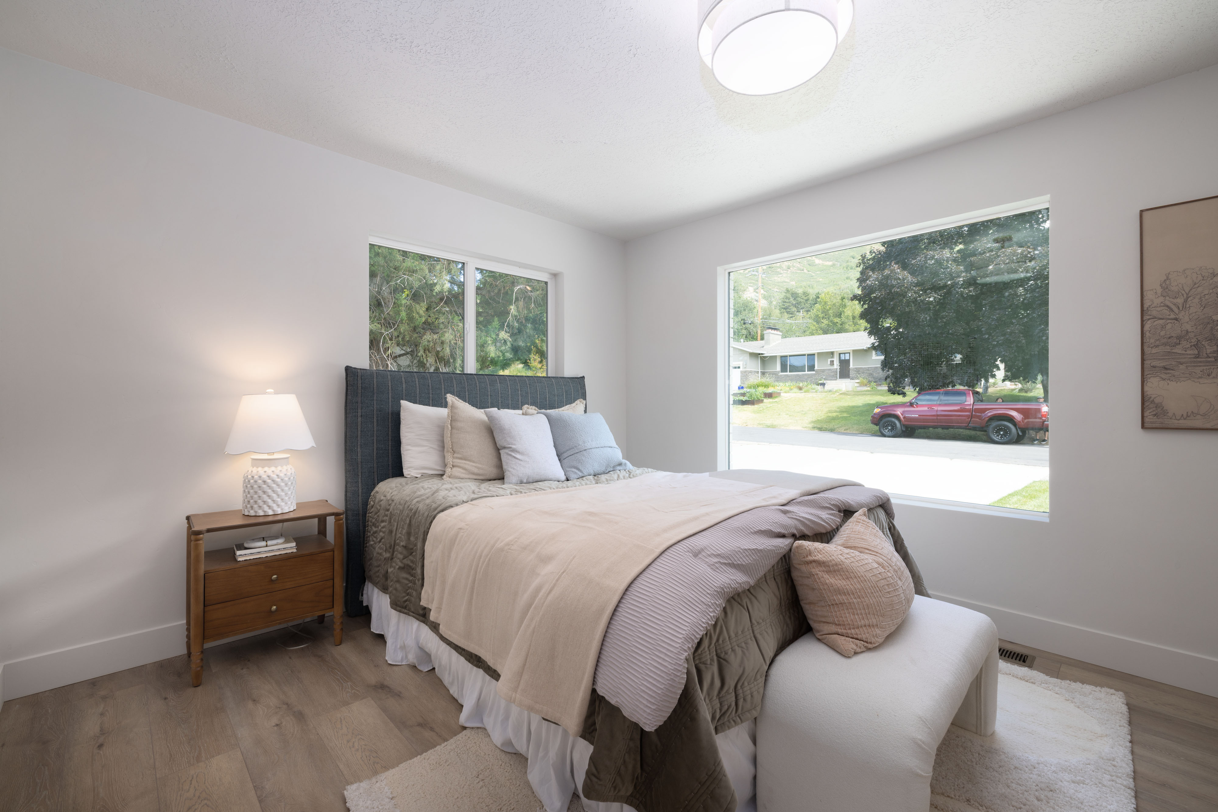 Bright room featuring a large picture window, wood-finish flooring, white baseboards, and a semi-flush mount ceiling light