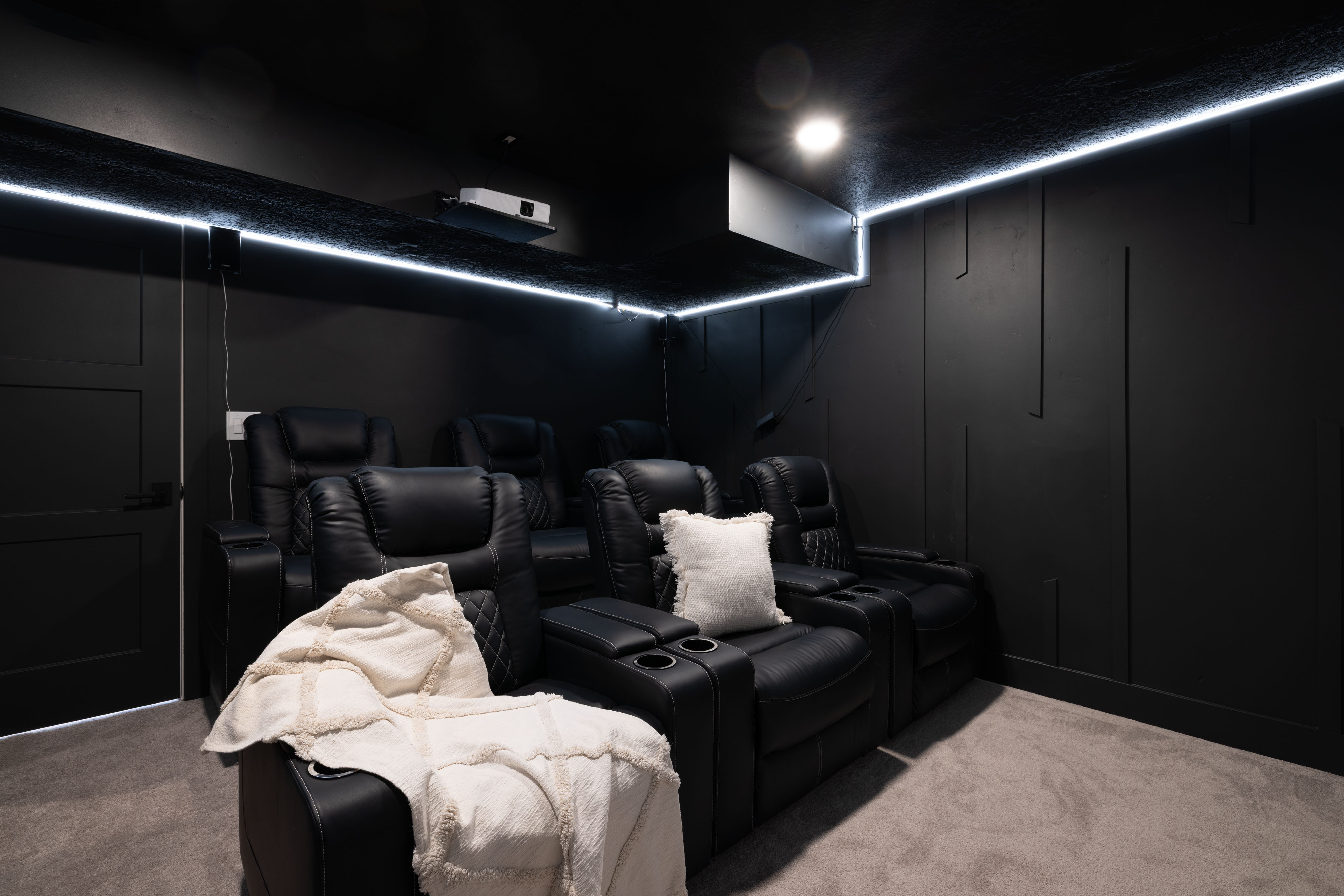 Dedicated media room featuring perimeter LED strip lighting, recessed ceiling lighting, and dark wall paneling