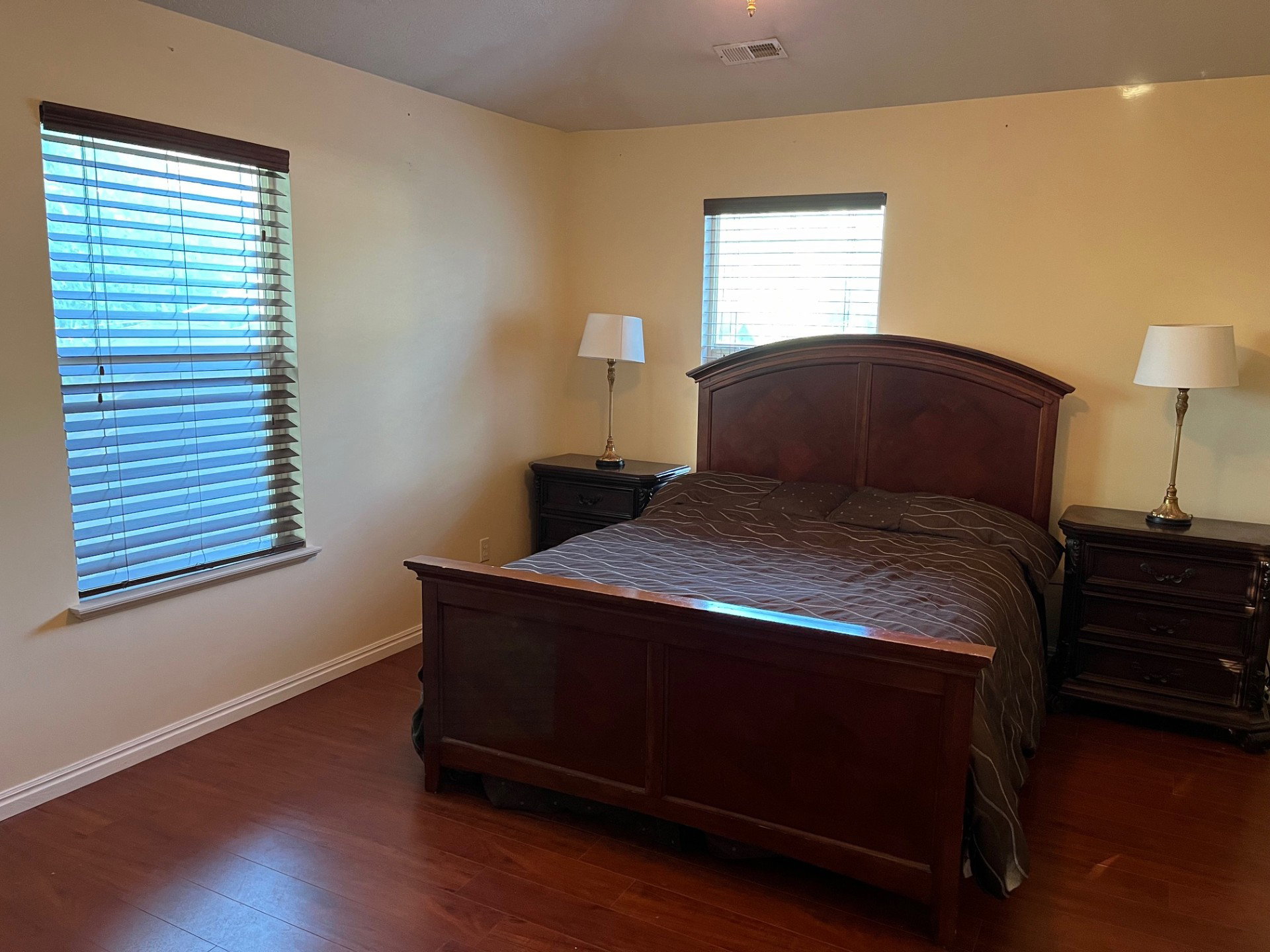 Room featuring wood-finish flooring, two windows with blinds, and light-toned walls