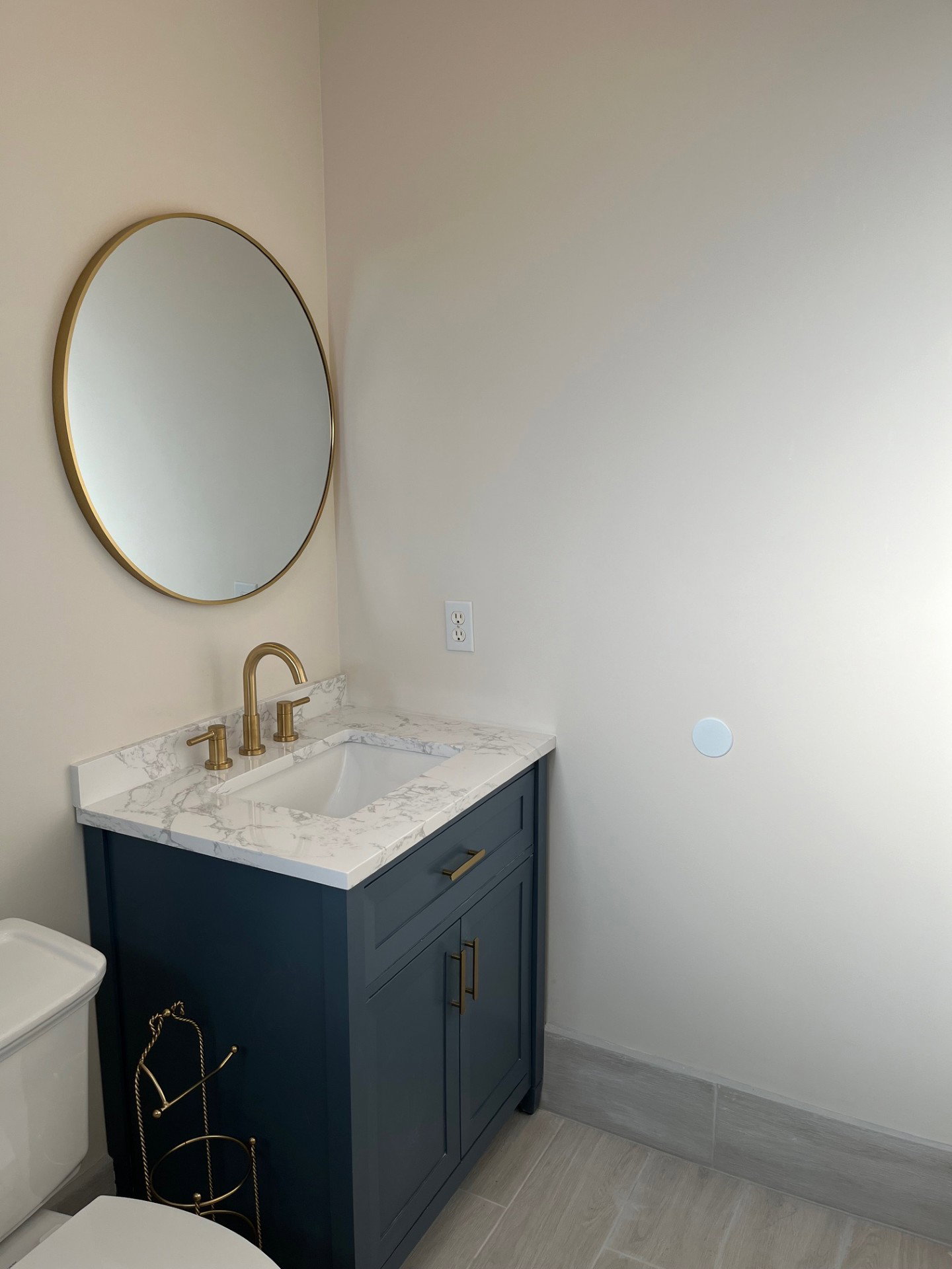 Vanity with a white countertop and integrated sink, gold-toned faucet, and dark blue cabinetry
