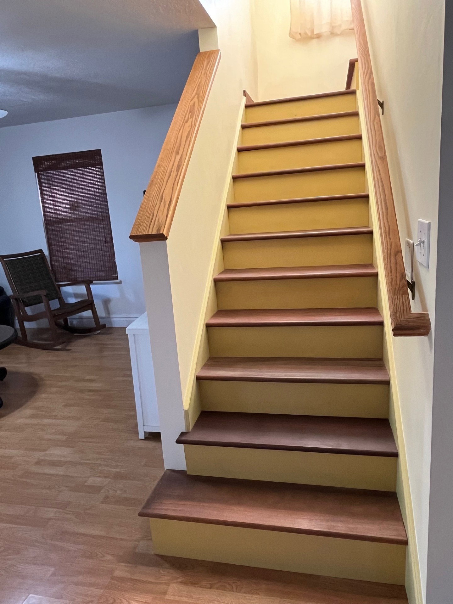 Staircase featuring wood-finish treads and handrails, complemented by light-toned risers