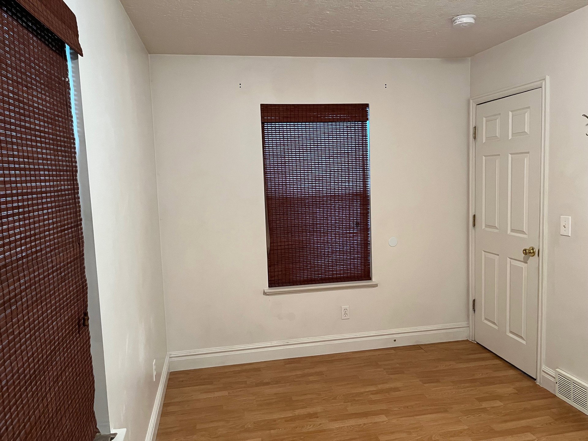 Room featuring light-toned walls, wood-finish flooring, and white baseboards