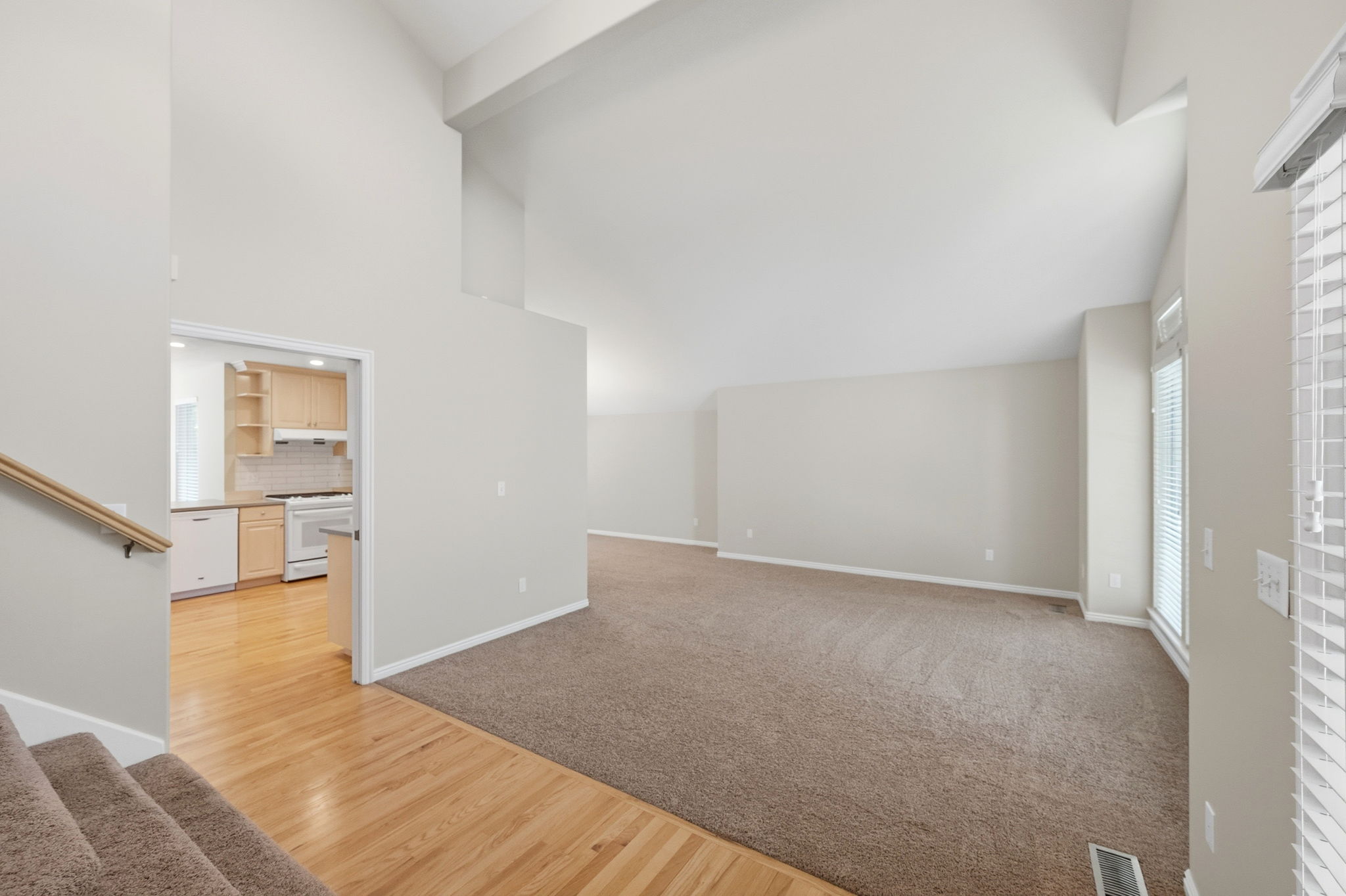 Vaulted ceilings enhance this living area with neutral carpeting and a bay window