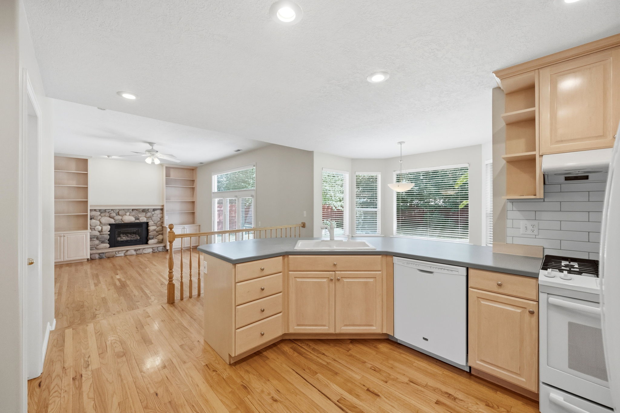 Kitchen featuring light wood cabinetry, white appliances, and a double basin sink