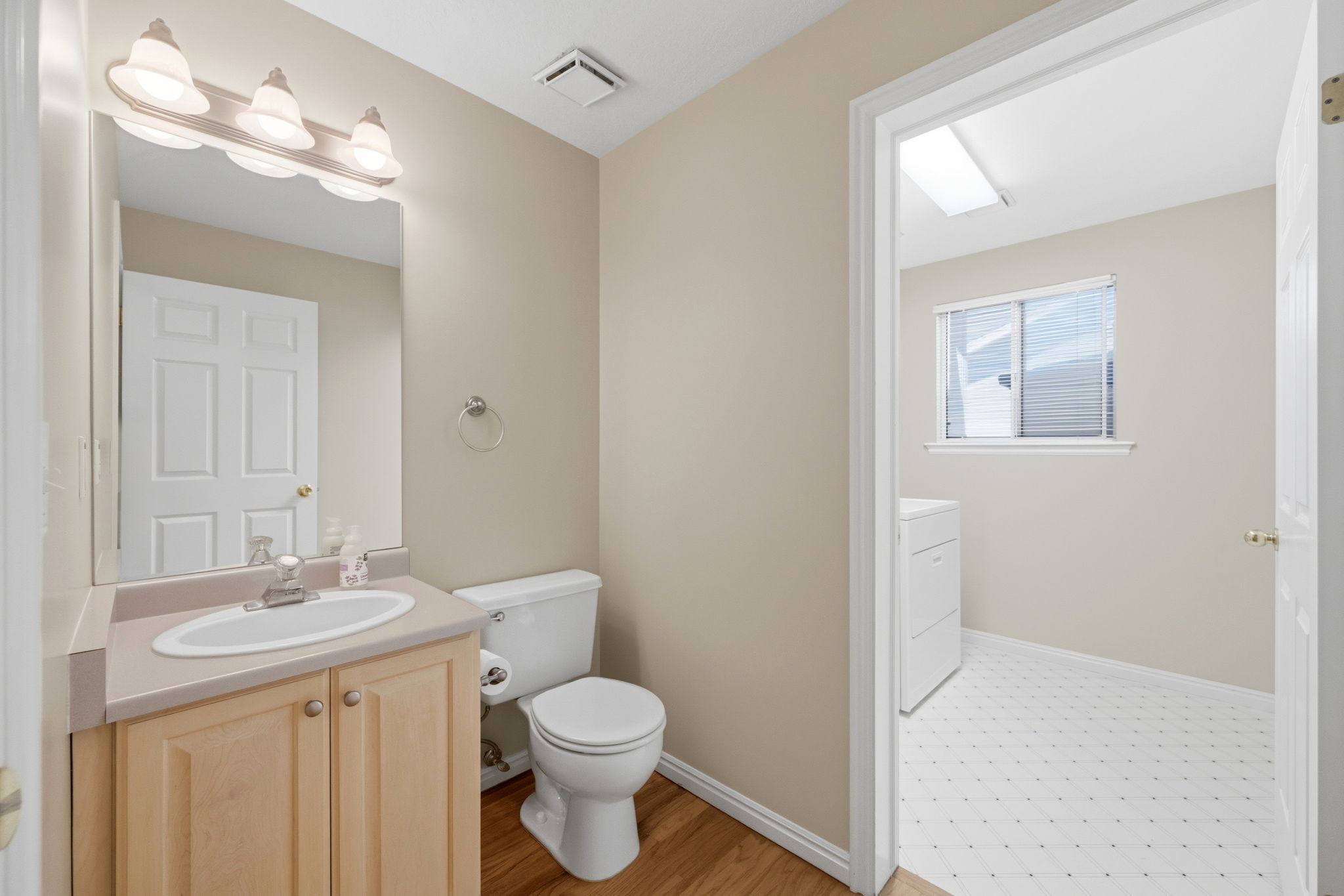 Vanity with integrated sink, wood-finish cabinetry, and a three-light fixture