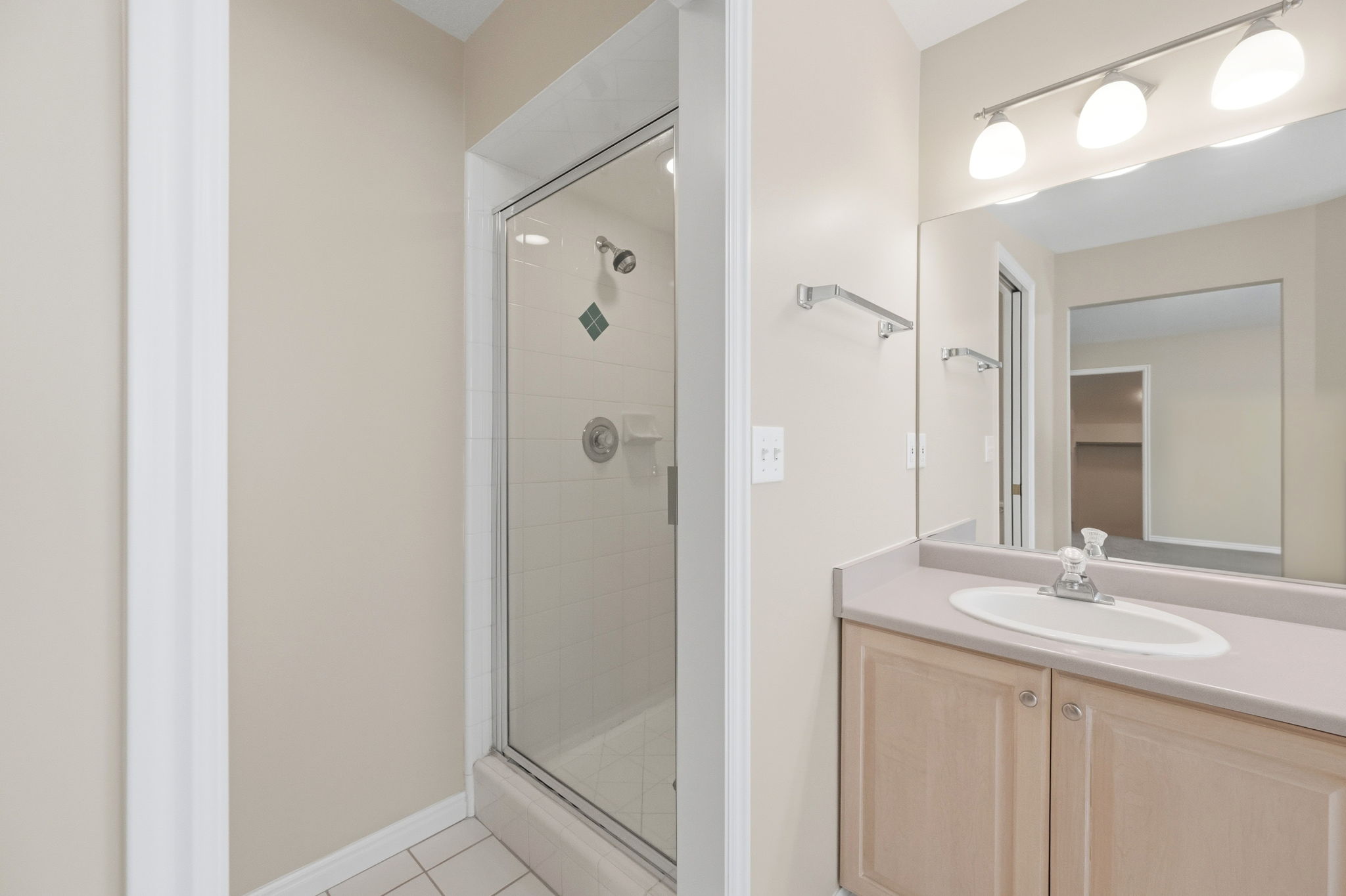 Bathroom featuring a walk-in shower with glass enclosure, single vanity with integrated sink, and overhead tri-light fixture