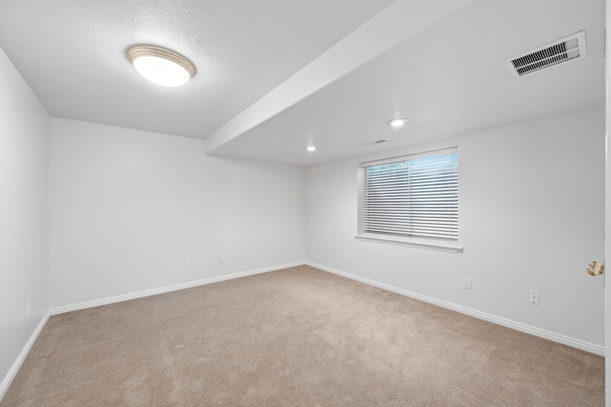 Neutral wall colors with recessed lighting and a window with horizontal blinds