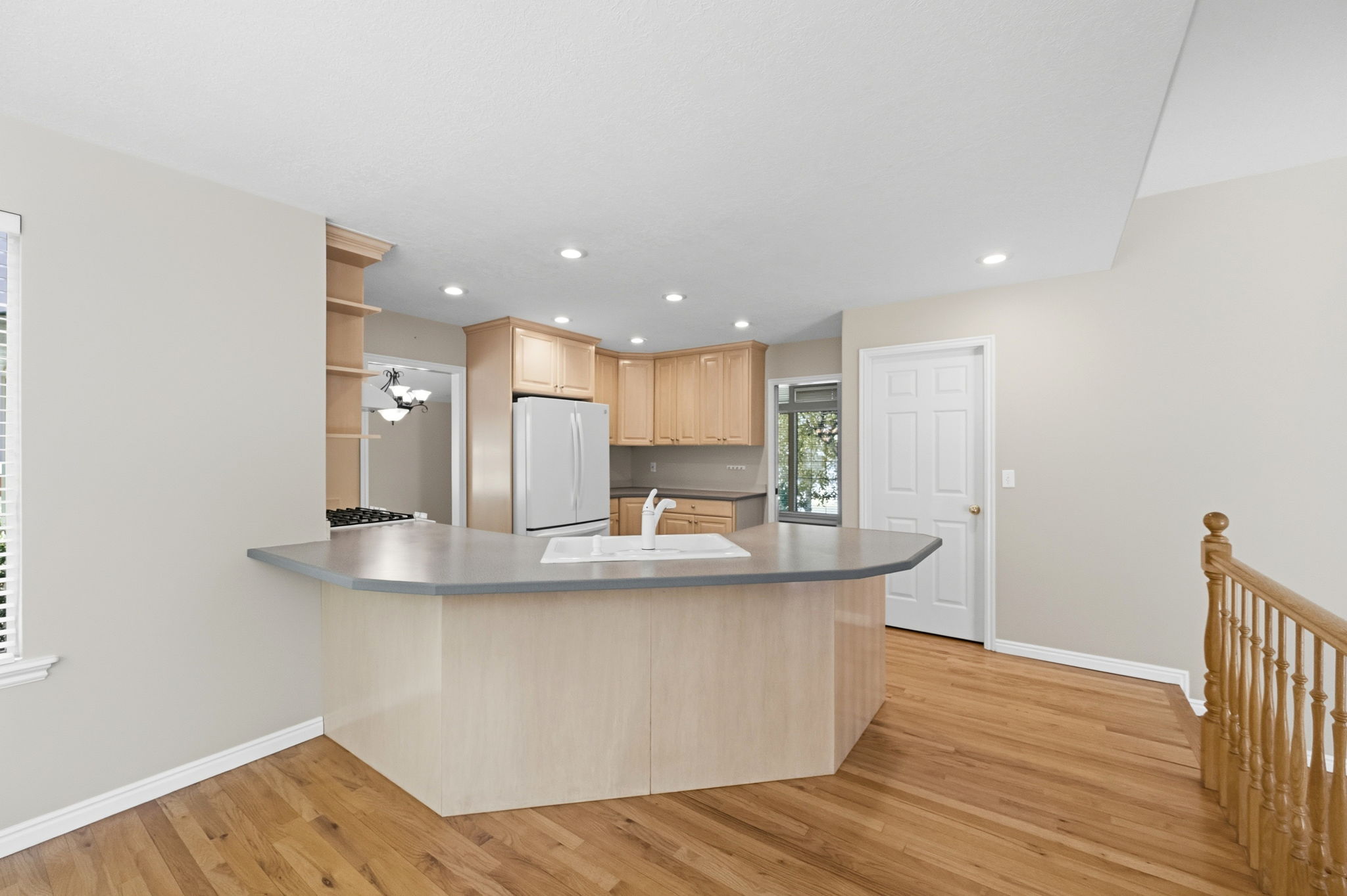 Kitchen with a peninsula island featuring a built-in sink and light-toned cabinetry
