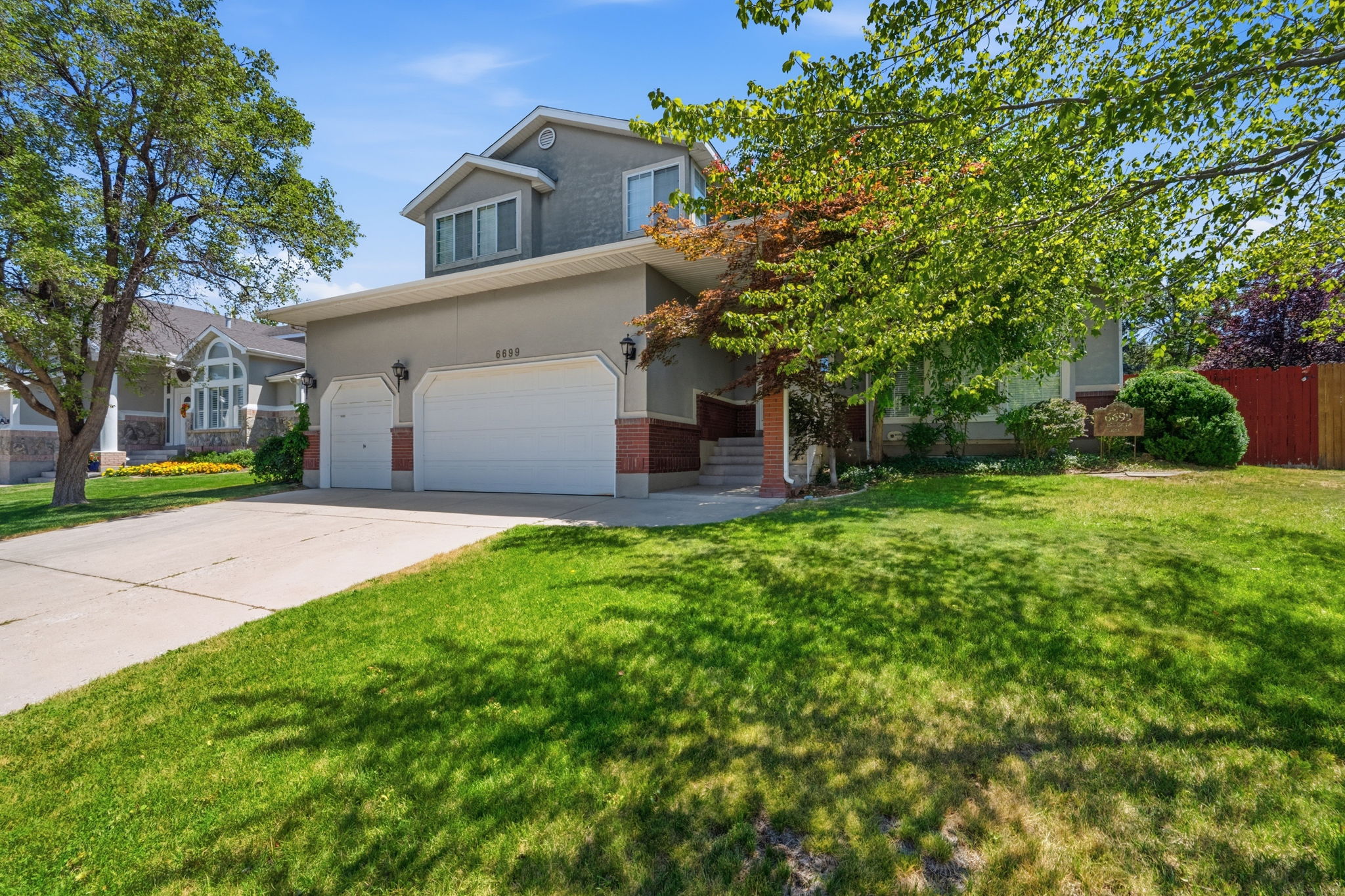 Contemporary stucco exterior with a brick accent foundation and a two-car garage