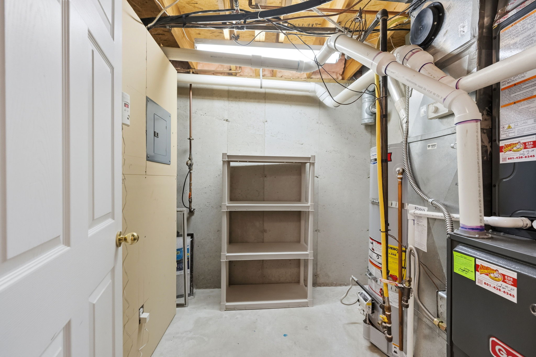 Utility room with exposed ceiling joists, concrete flooring, and a comprehensive mechanical system