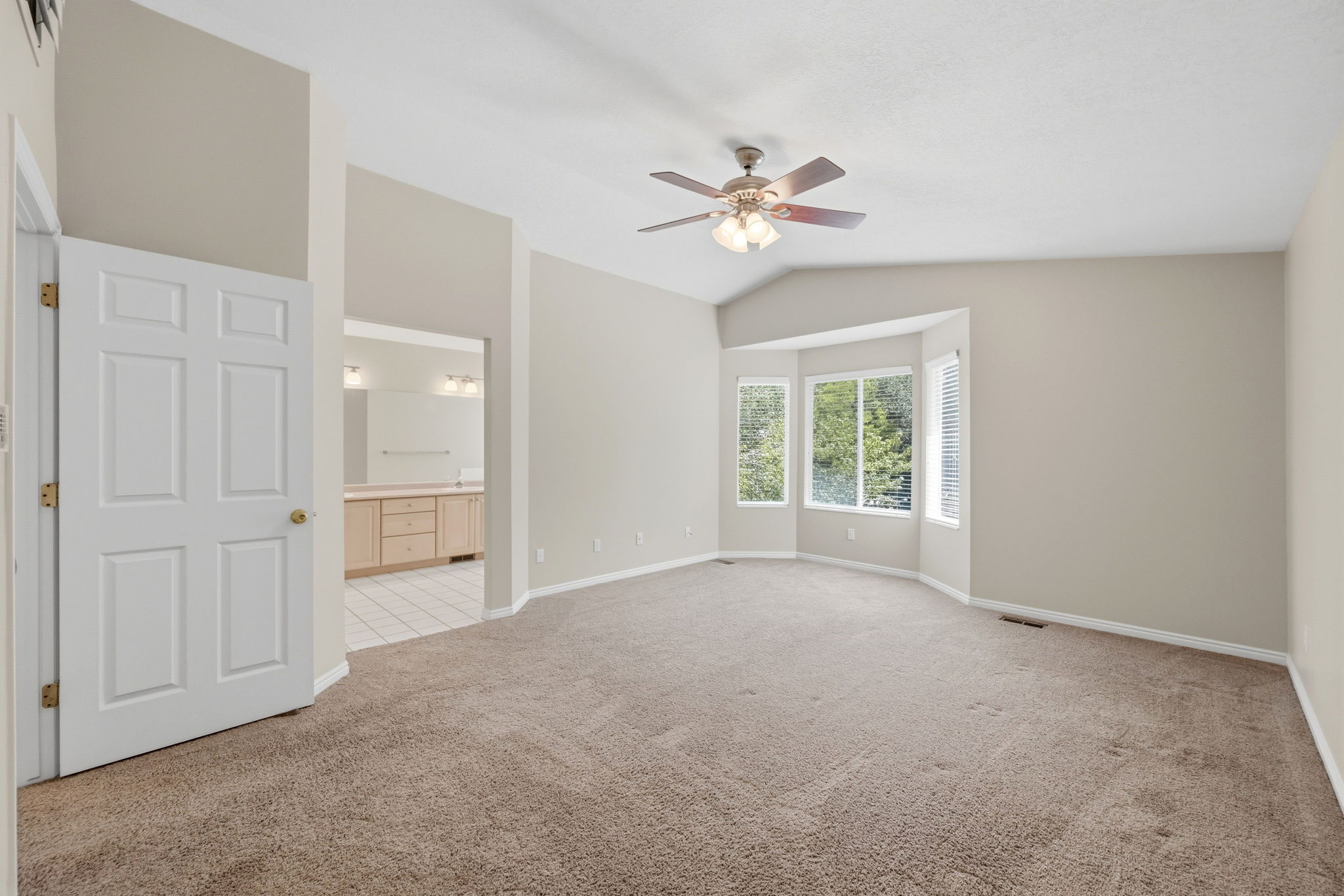 Spacious room featuring vaulted ceilings and a ceiling fan
